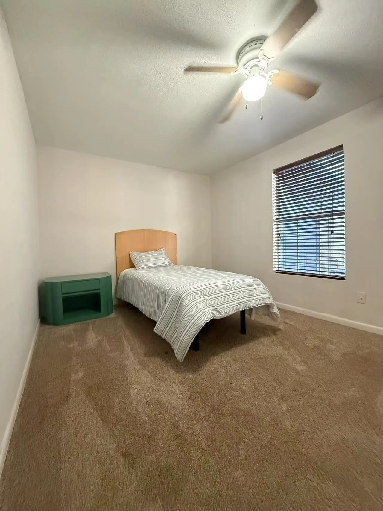 Bedroom featuring light brown carpet flooring, a ceiling fan with integrated lighting, and a window with horizontal blinds