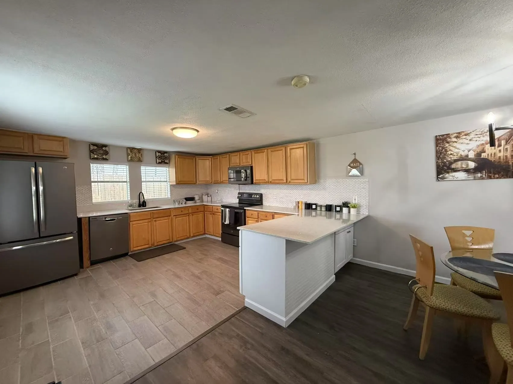 Kitchen featuring light wood cabinetry, stainless steel appliances, a white tile backsplash, and light-colored countertops
