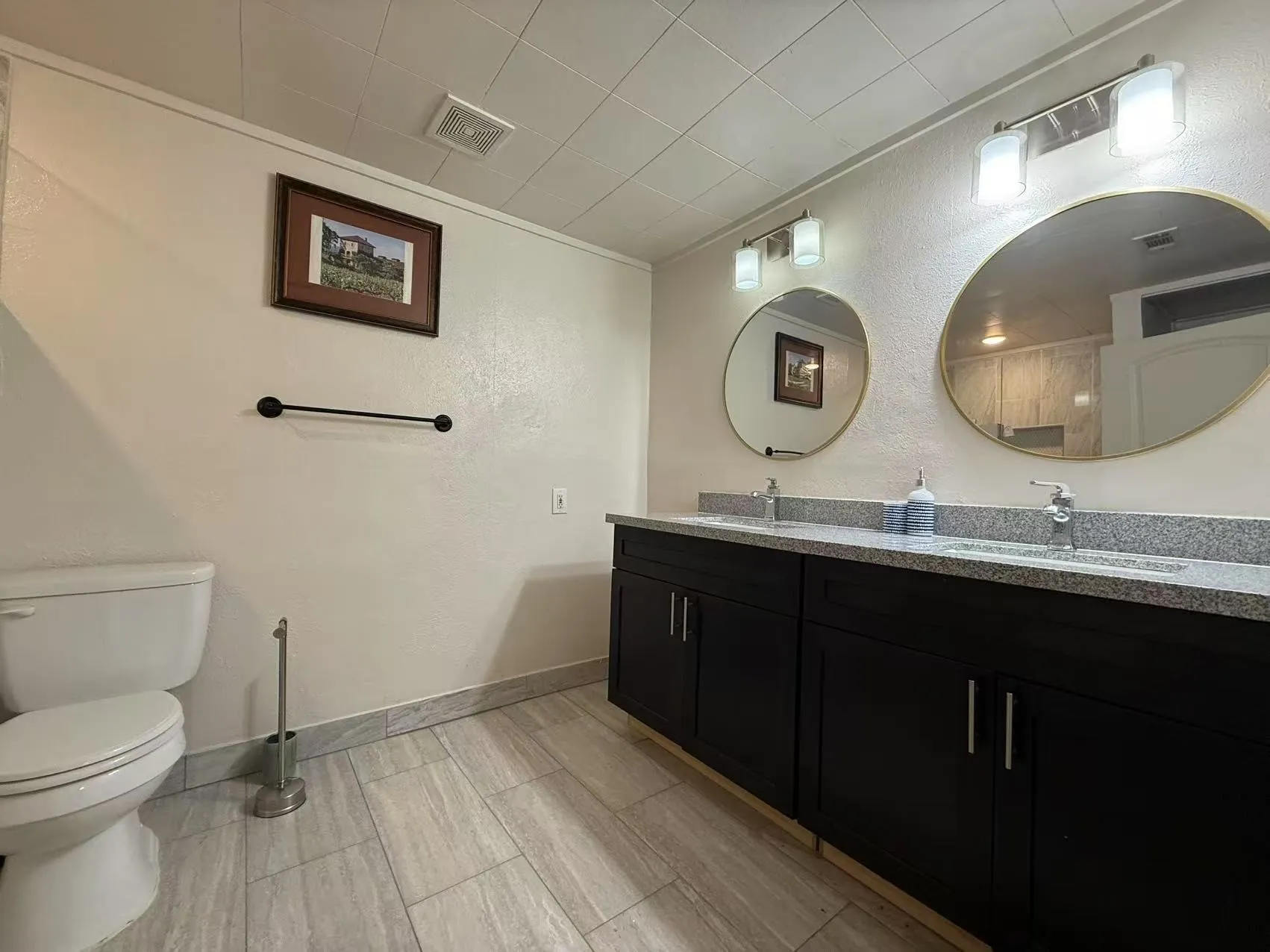 Dual vanity with black cabinetry, light gray countertop, and undermount sinks