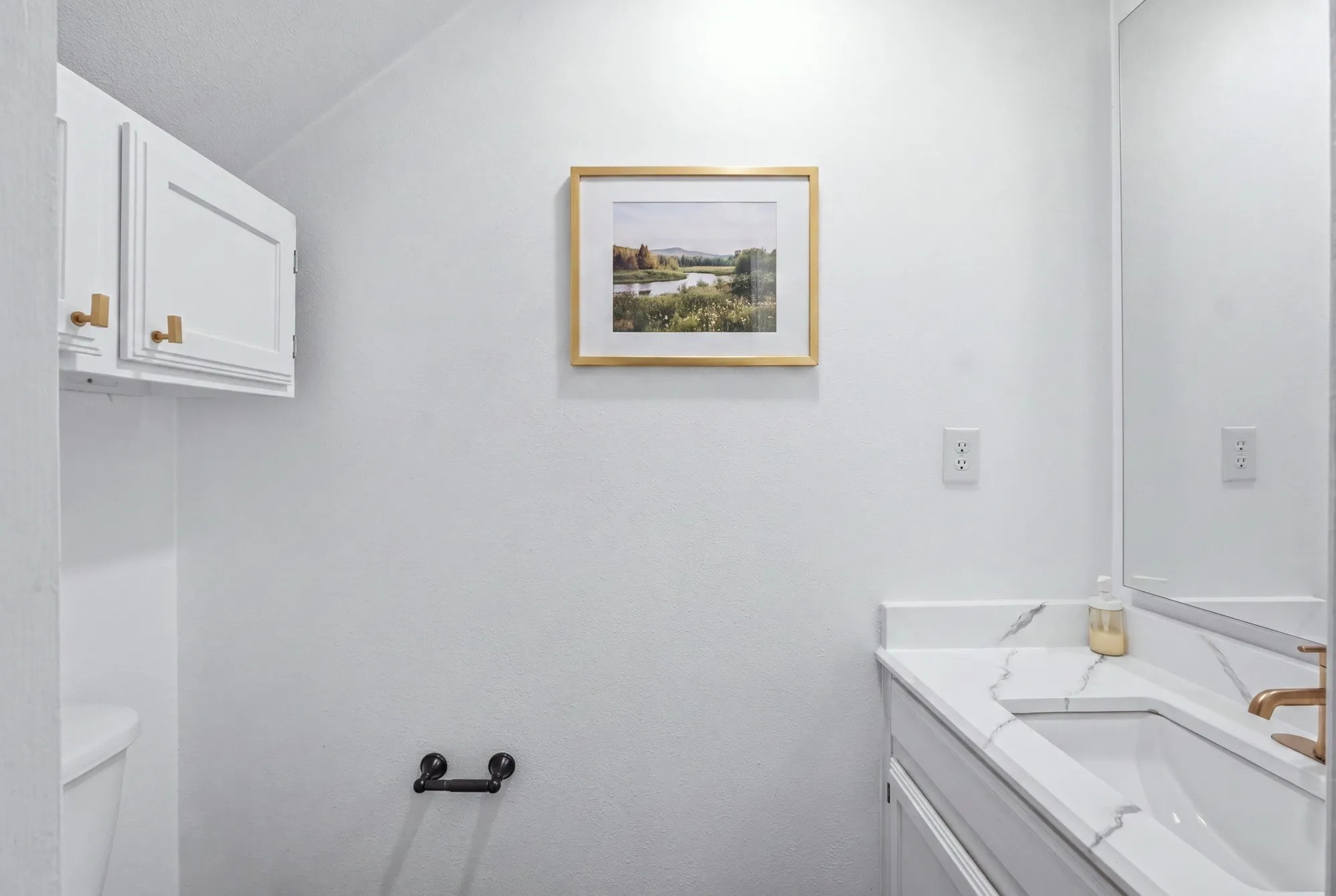 White vanity with a quartz countertop, integrated rectangular sink, and gold-finish faucet