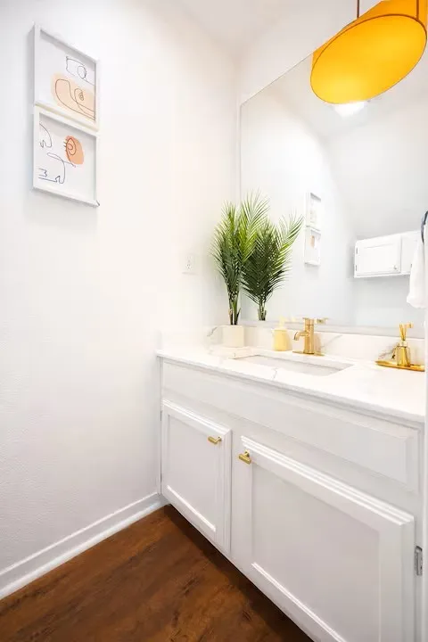 White vanity featuring a single basin, gold-finish faucet, and coordinating hardware