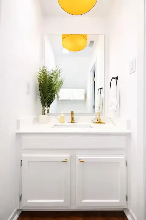 White vanity with gold-finish hardware and a white countertop