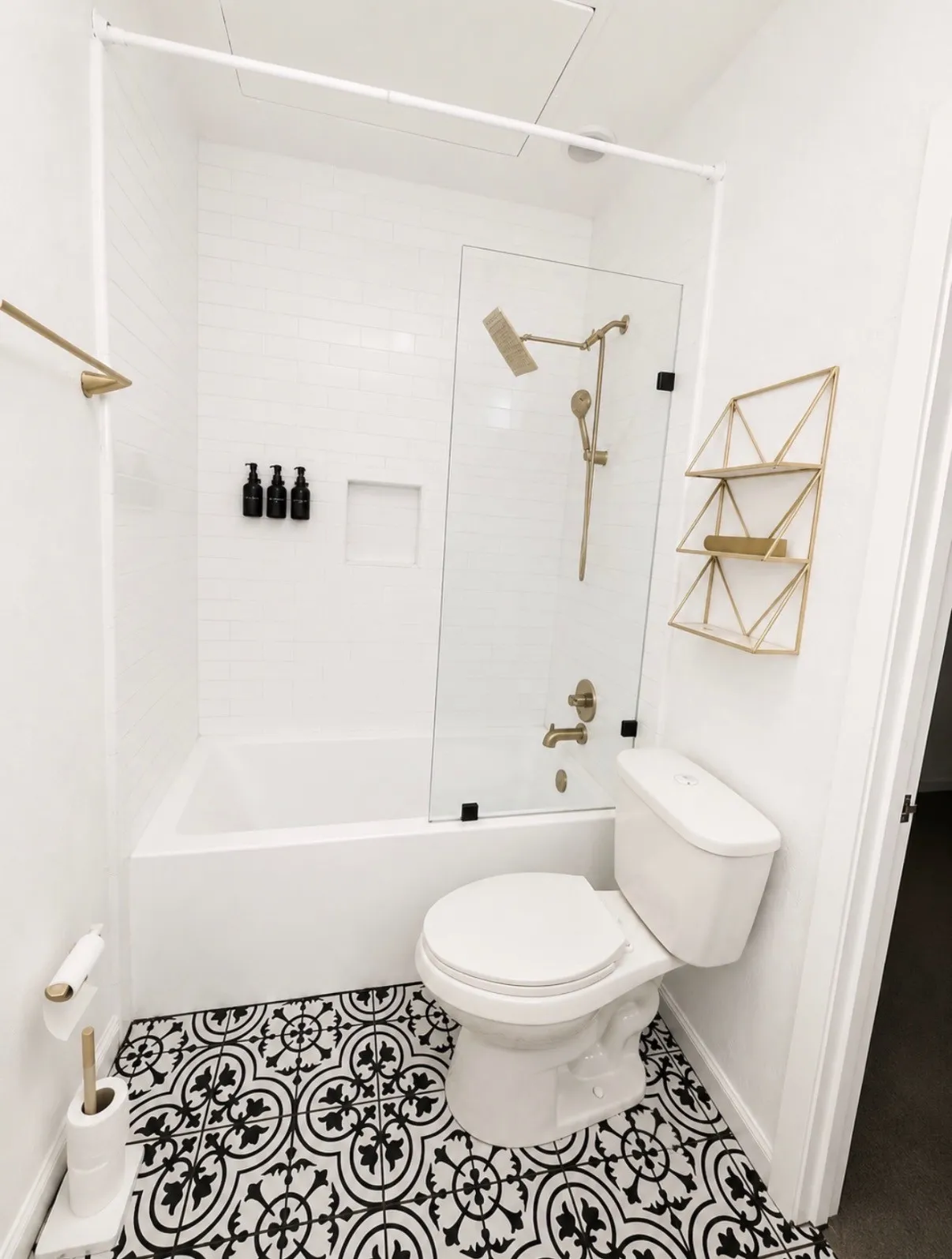 White subway tile surround with built-in niche, glass shower partition, and gold-finish fixtures