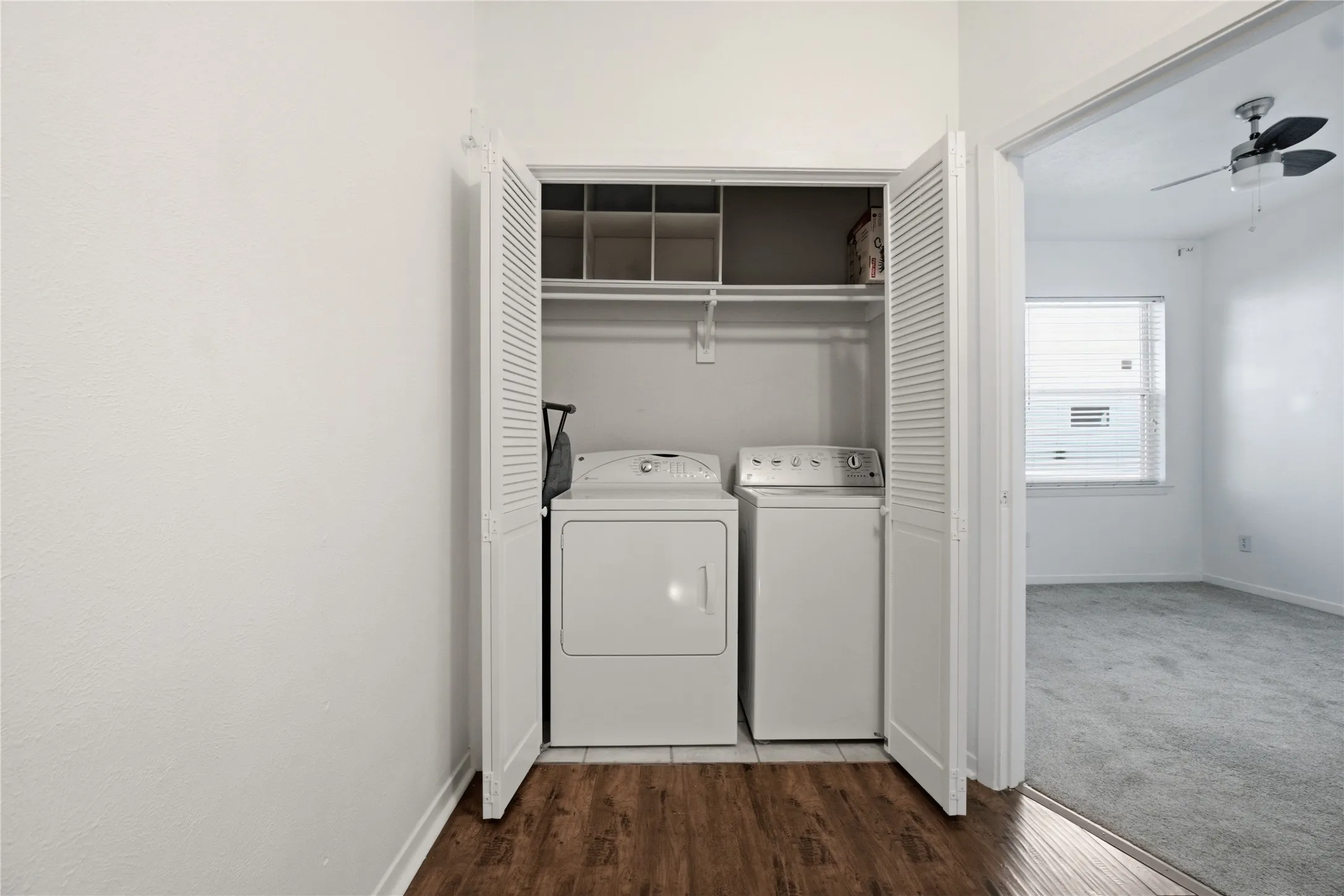 Laundry closet featuring a full-size washer and dryer, wood-finish flooring, and upper shelving