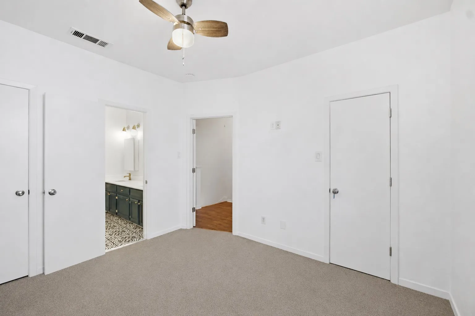 Carpeted flooring complemented by a ceiling fan with integrated lighting