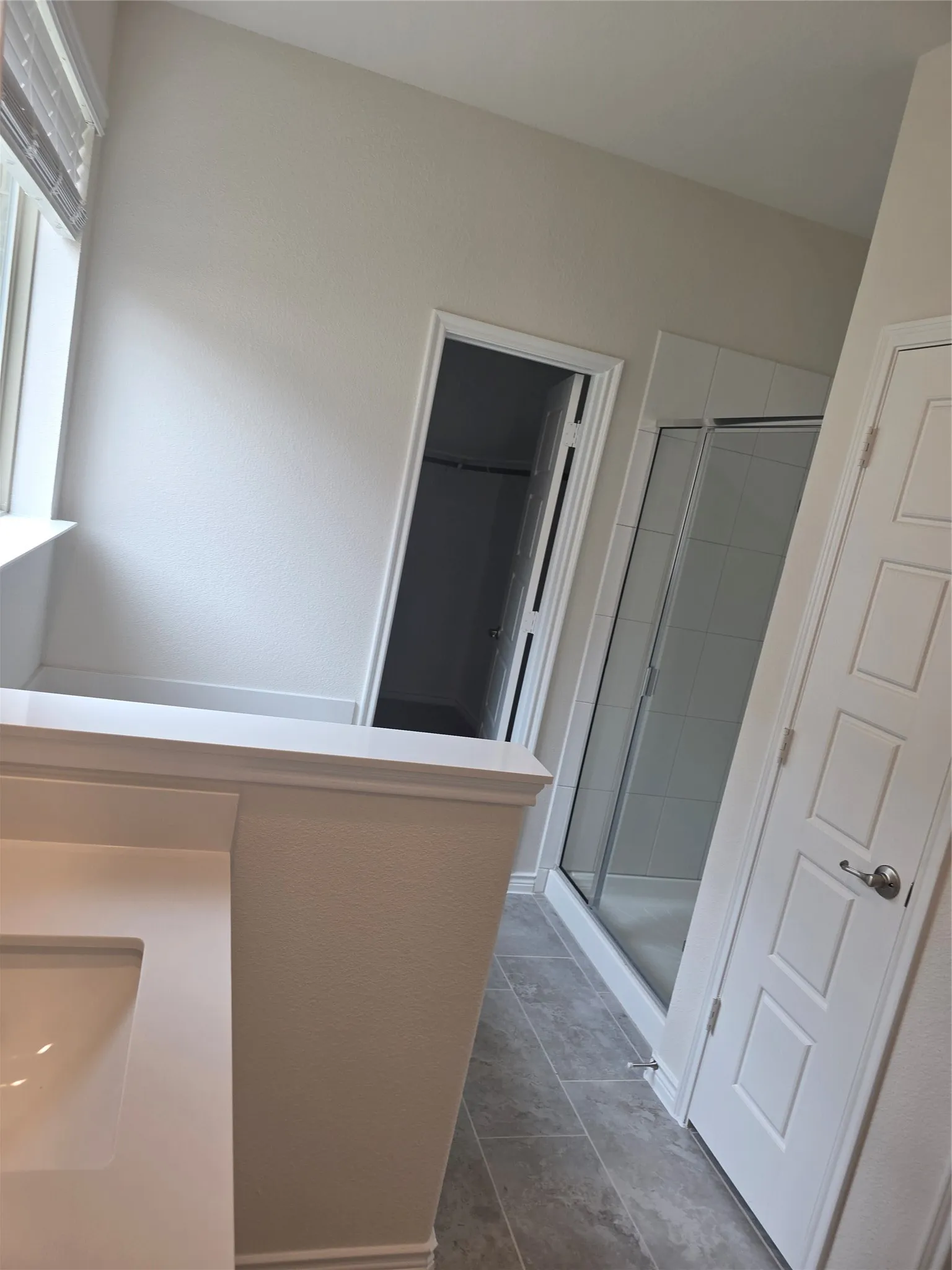 Contemporary bathroom featuring a vanity with integrated sink, a glass-enclosed shower, a privacy commode, and large format tile flooring