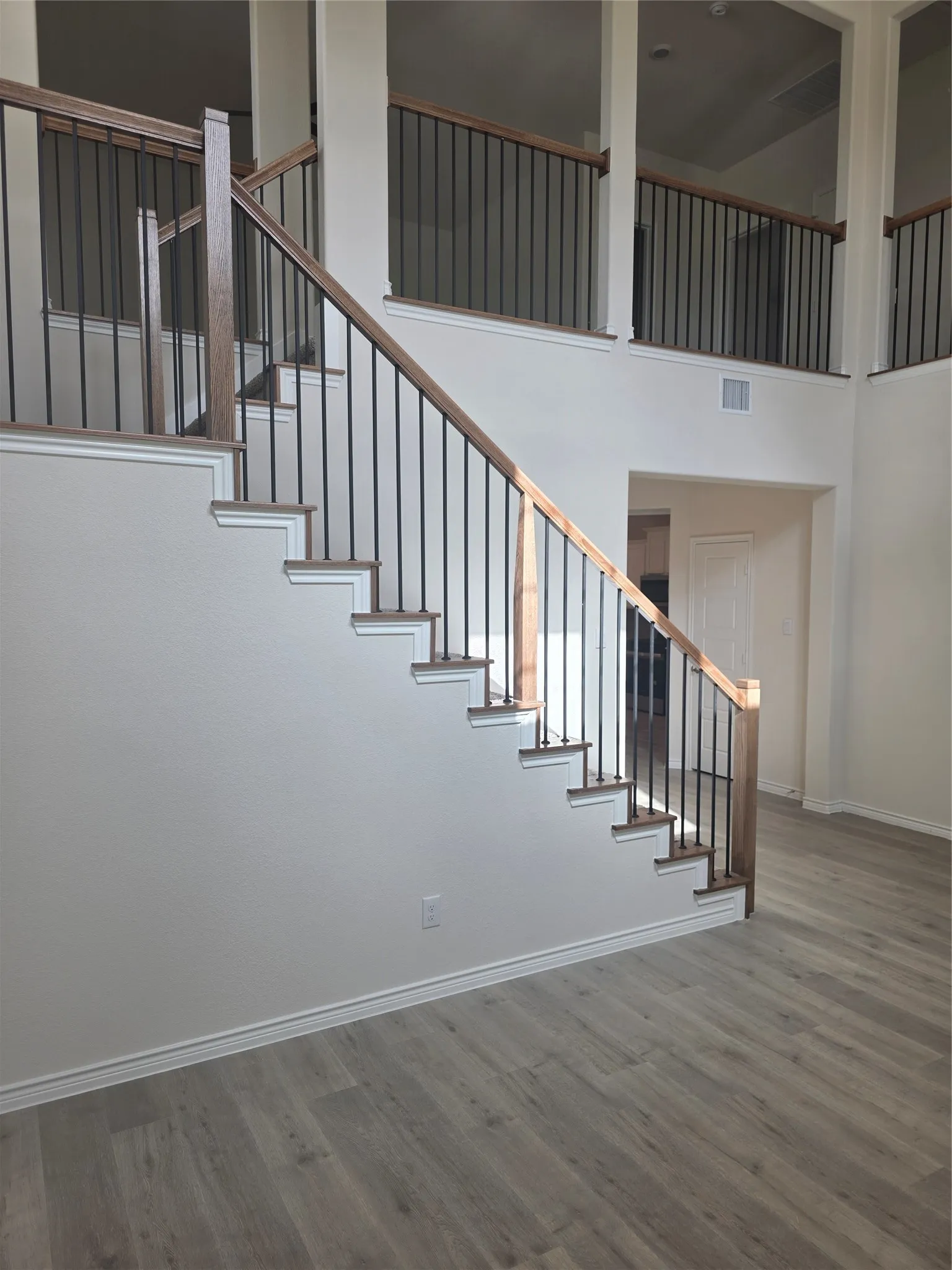 Staircase featuring wood-finish handrails and black metal balusters