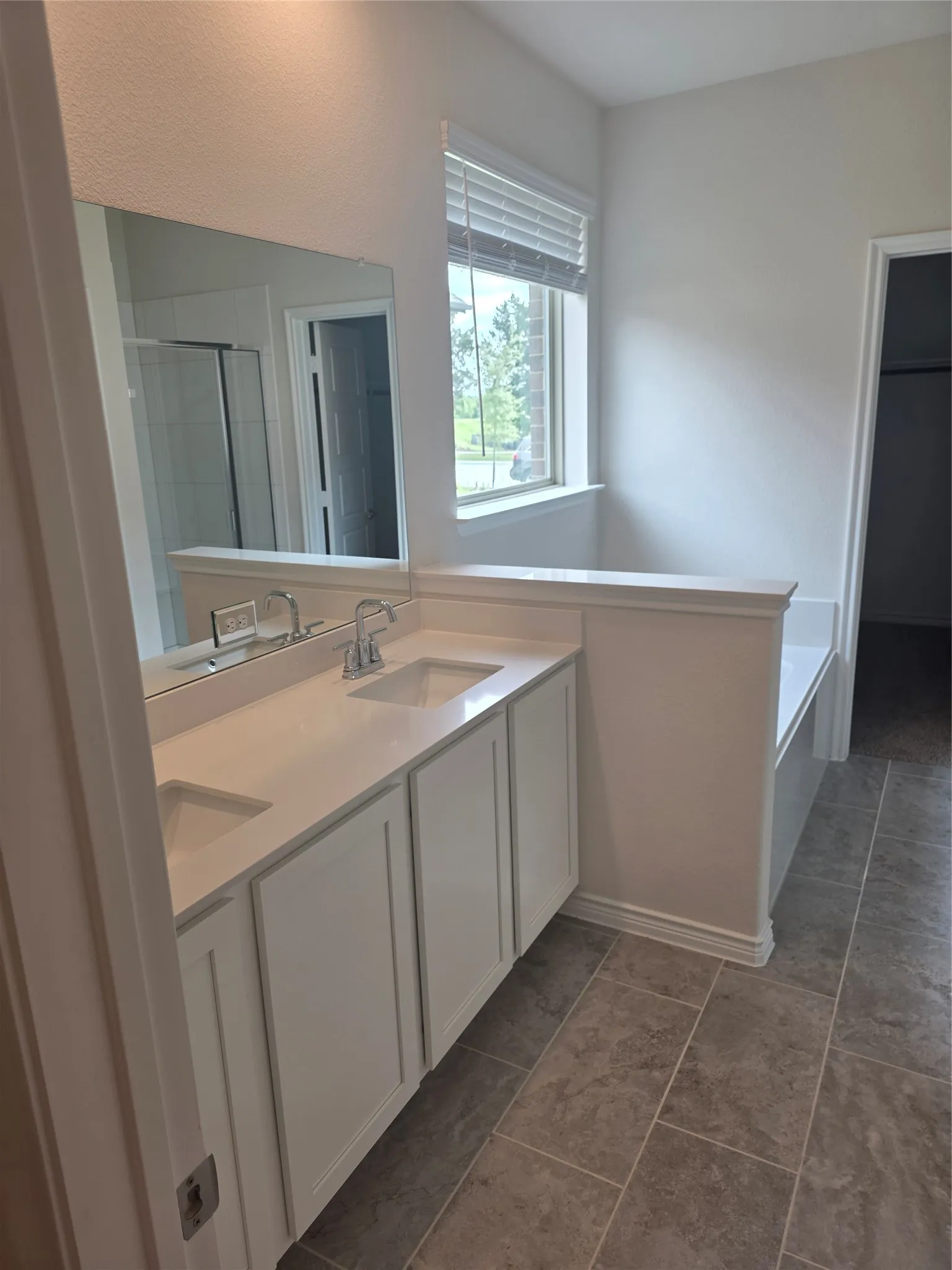 Dual vanity with white cabinetry, integrated sinks, chrome fixtures, and a large wall-mounted mirror