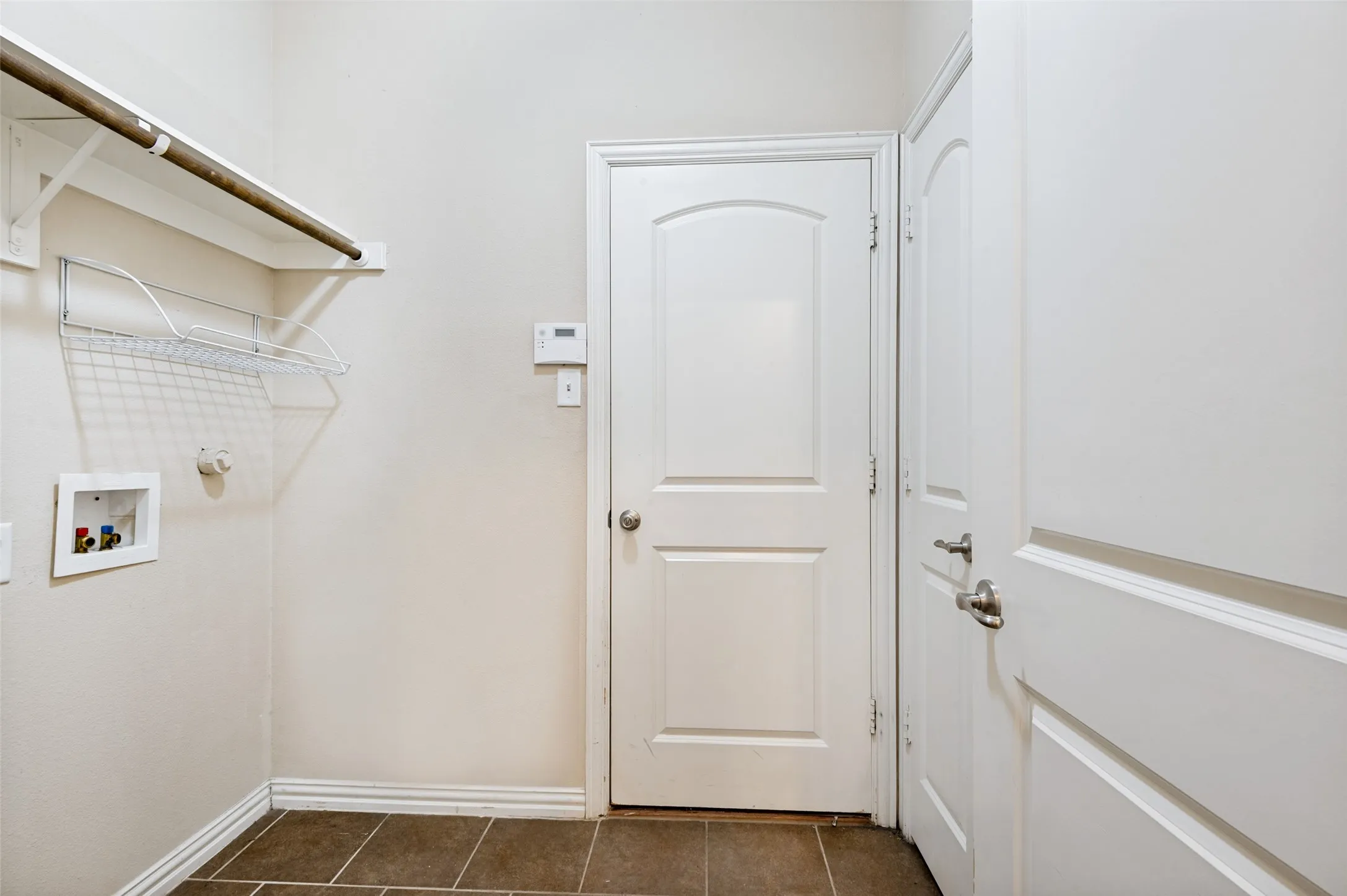 Dedicated laundry area featuring a hanging rod, wire shelving, and appliance hookups