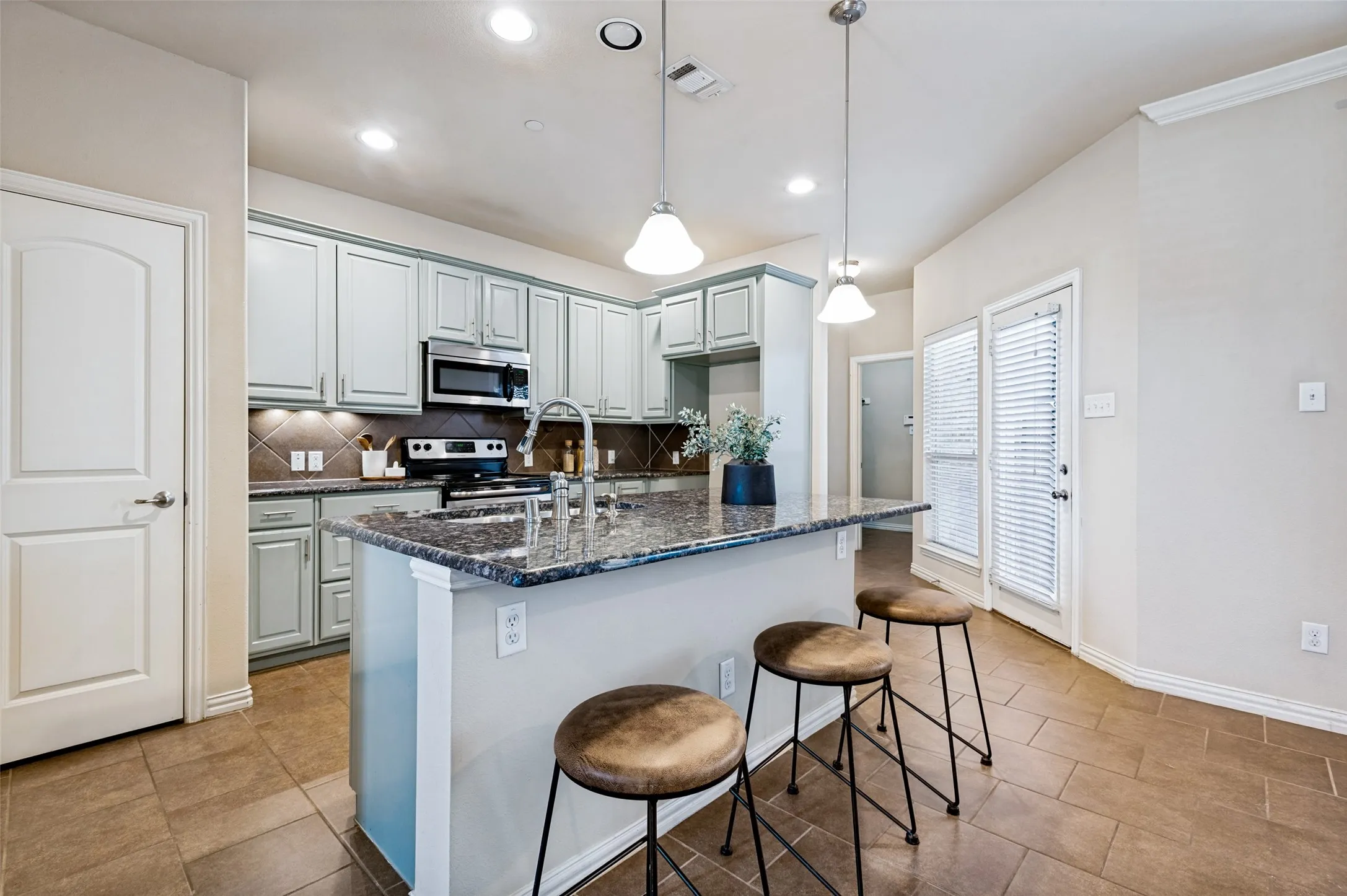 Kitchen features granite countertops, painted cabinetry, stainless steel appliances, and a large center island with space for seating.