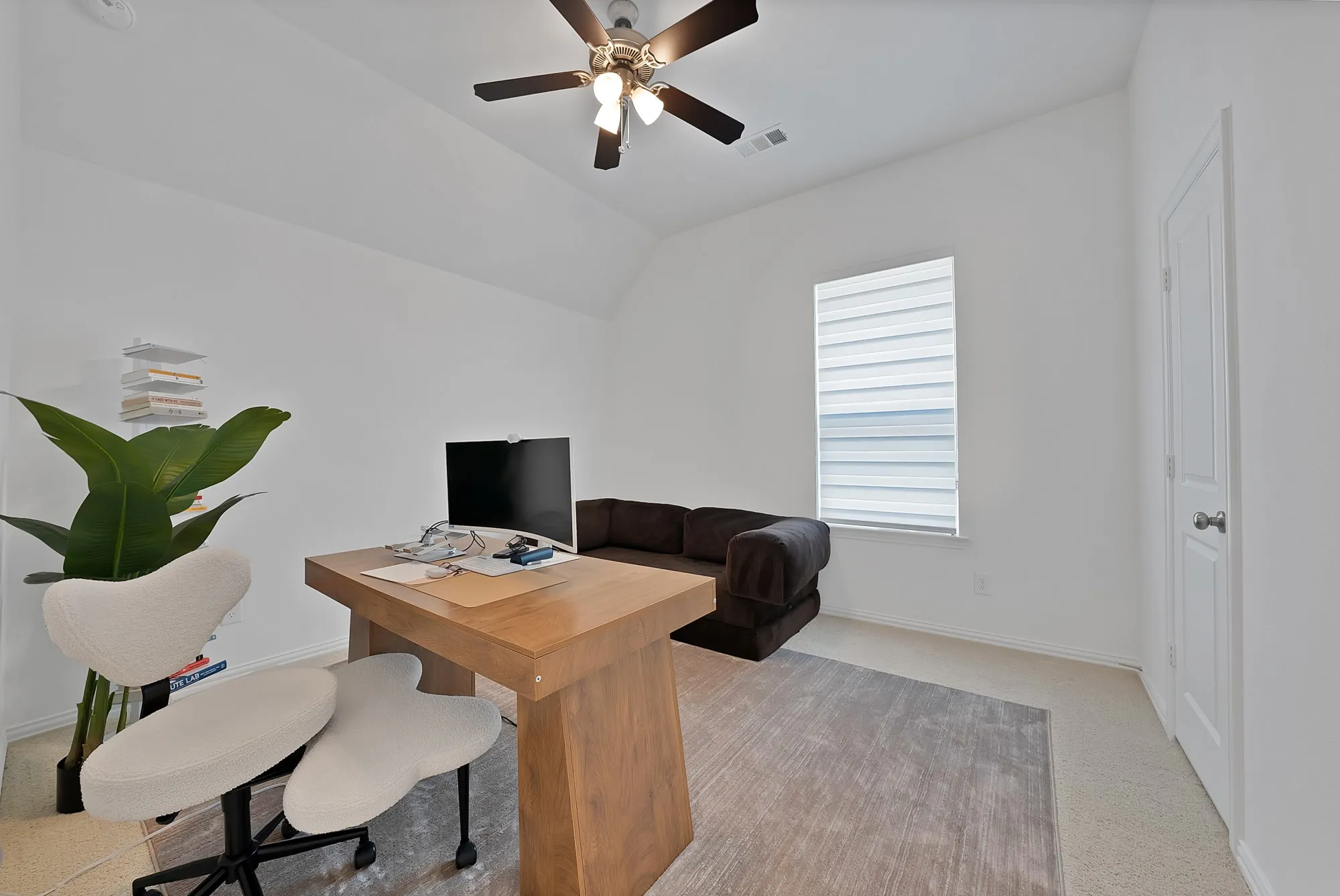 Room featuring a vaulted ceiling with a ceiling fan, a single window with blinds, and light-toned wall-to-wall carpeting