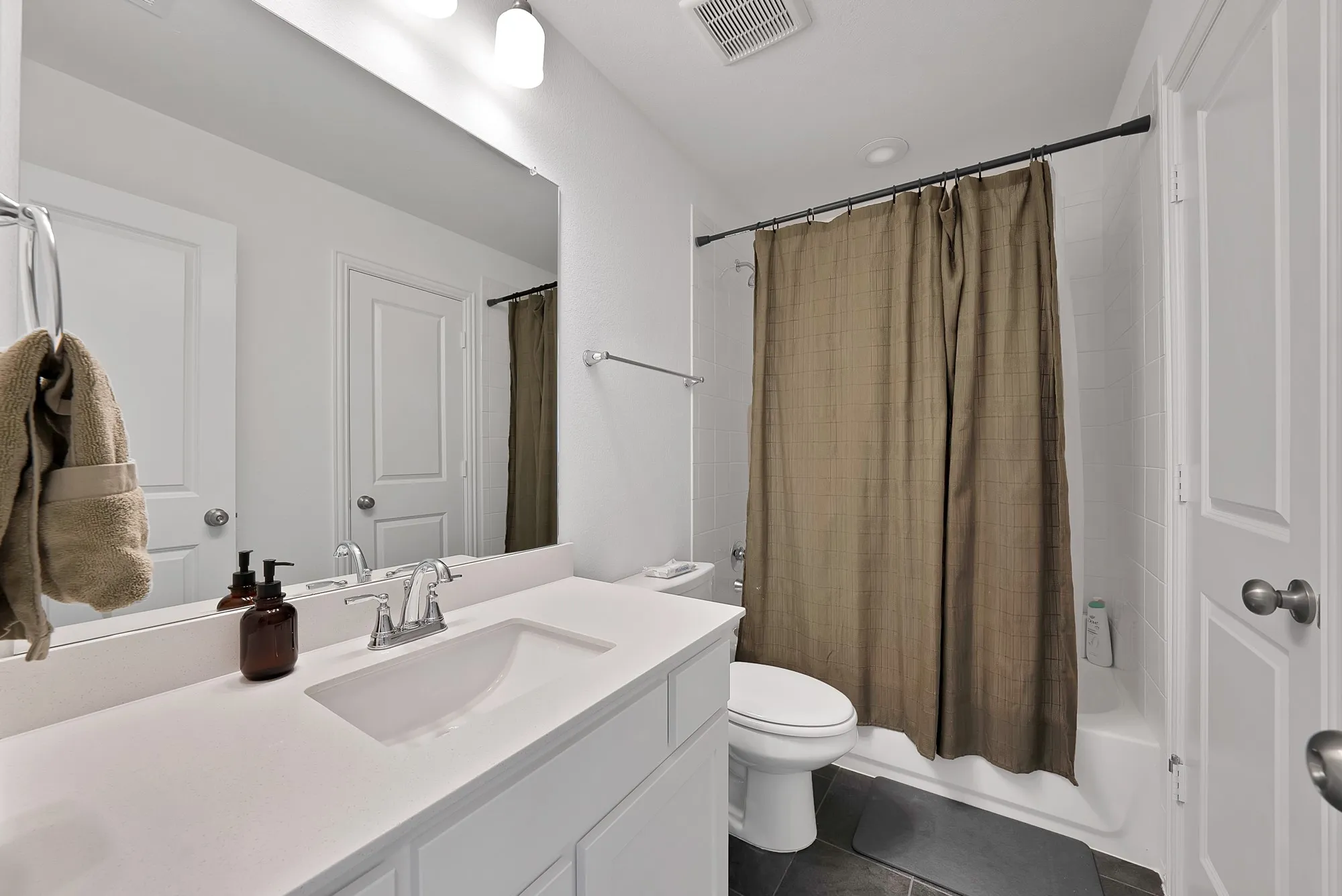Bathroom vanity featuring an integrated sink, polished chrome faucet, and expansive wall mirror