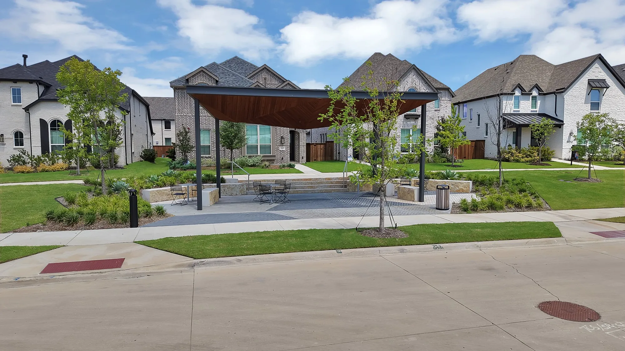 Community gathering space featuring a modern pergola, paved seating area, and integrated planters