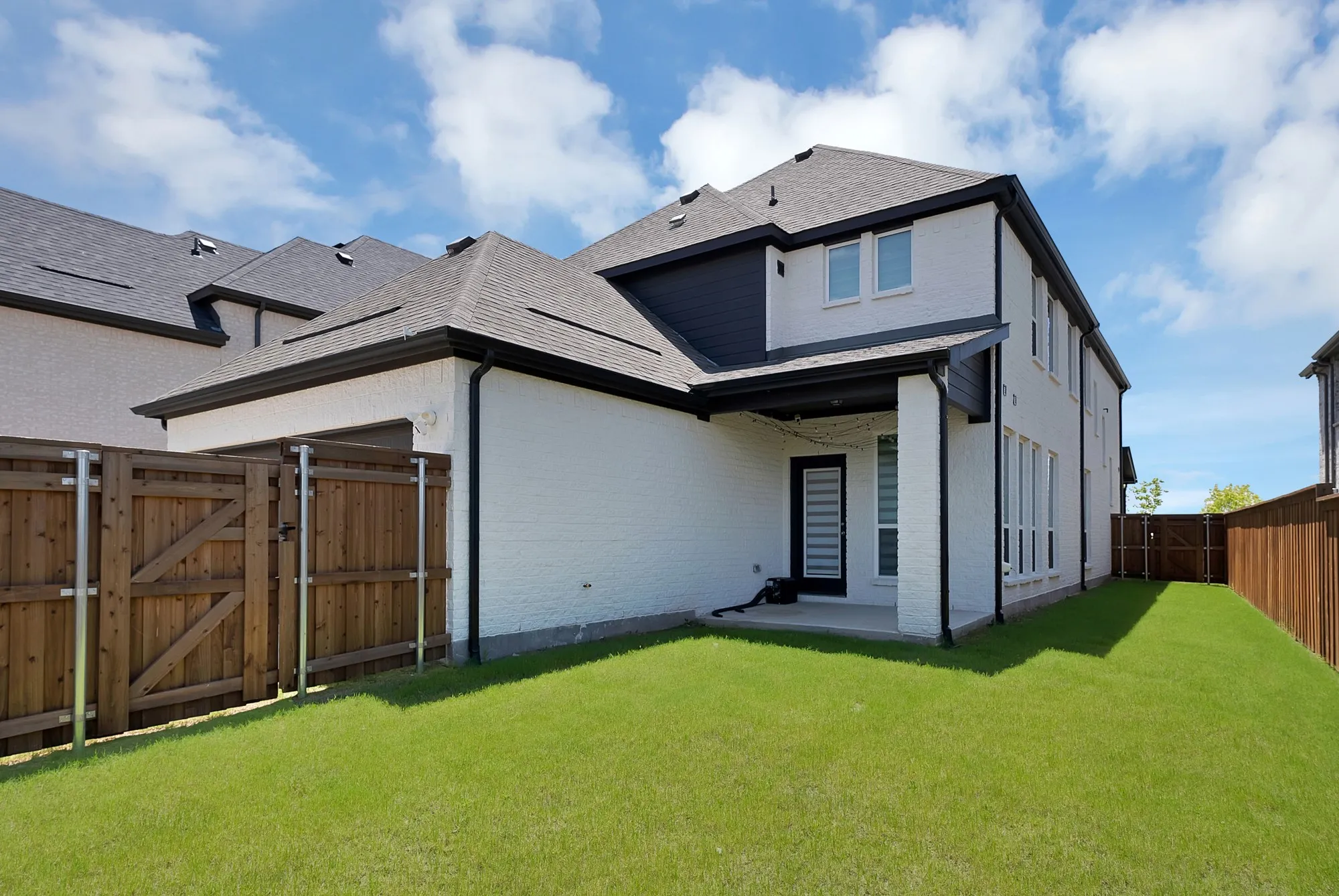 Spacious backyard featuring a manicured lawn, full privacy fencing, and a covered patio area