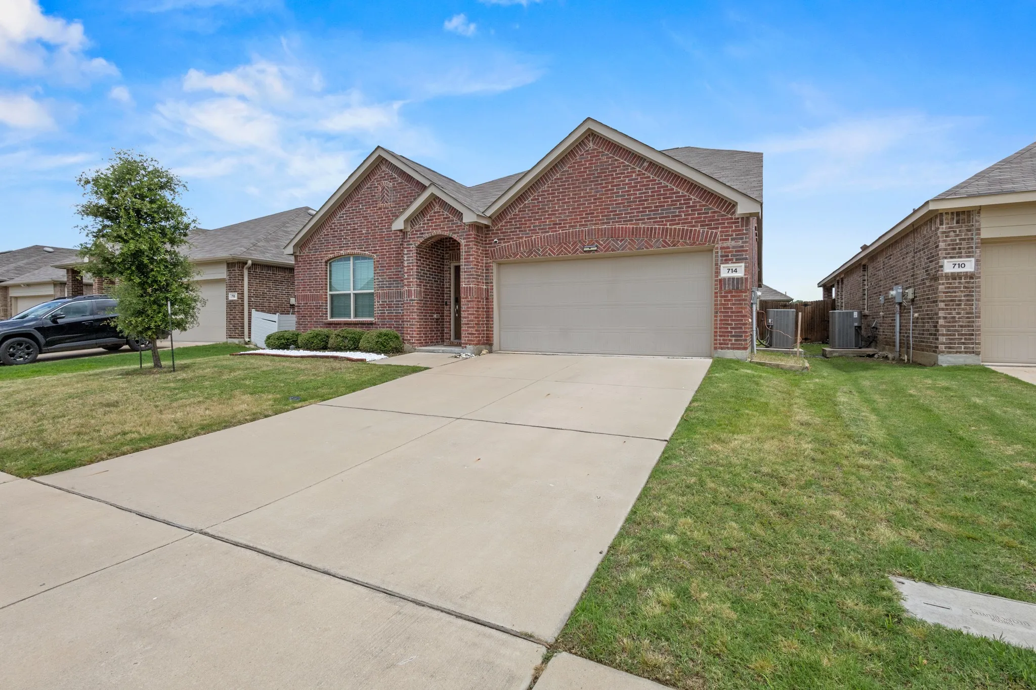 Brick exterior with an arched entry, a two-car garage, and a concrete driveway