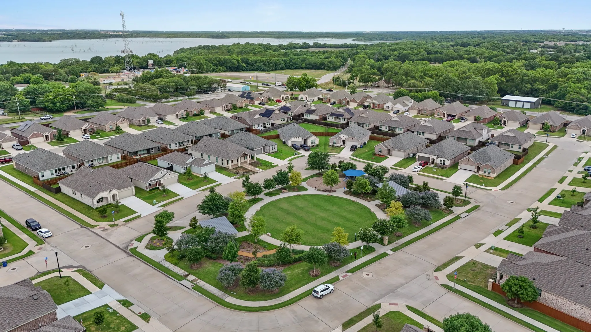 Aerial view of a residential community featuring a central green space with walking paths and mature landscaping
