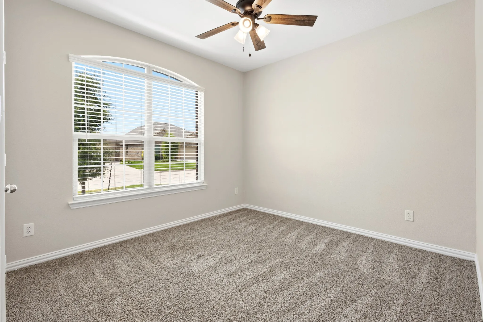 Room featuring an arched window with blinds, neutral wall paint, and patterned carpet flooring