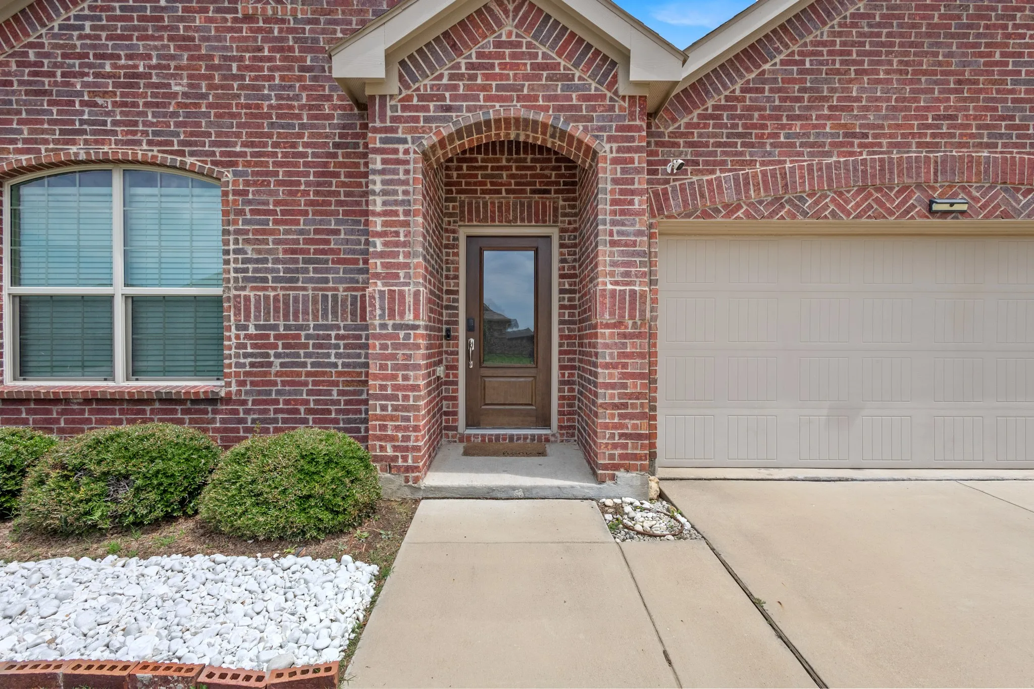 Brick facade featuring a recessed entry with an arched accent and a brown paneled door with glass insert