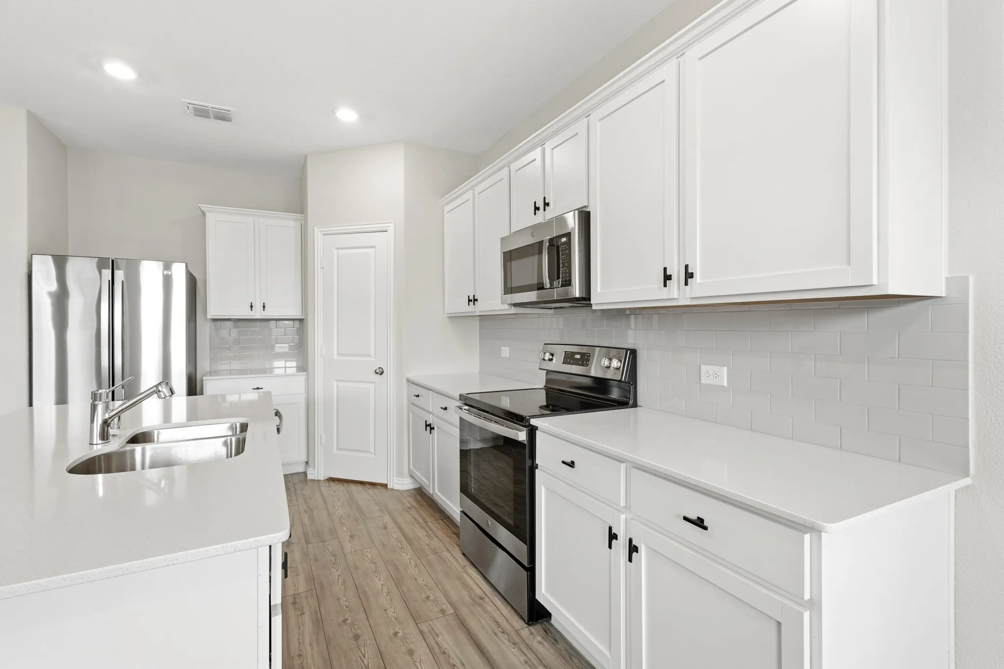 Modern kitchen featuring white cabinetry, light-toned countertops, and wood-finish flooring
