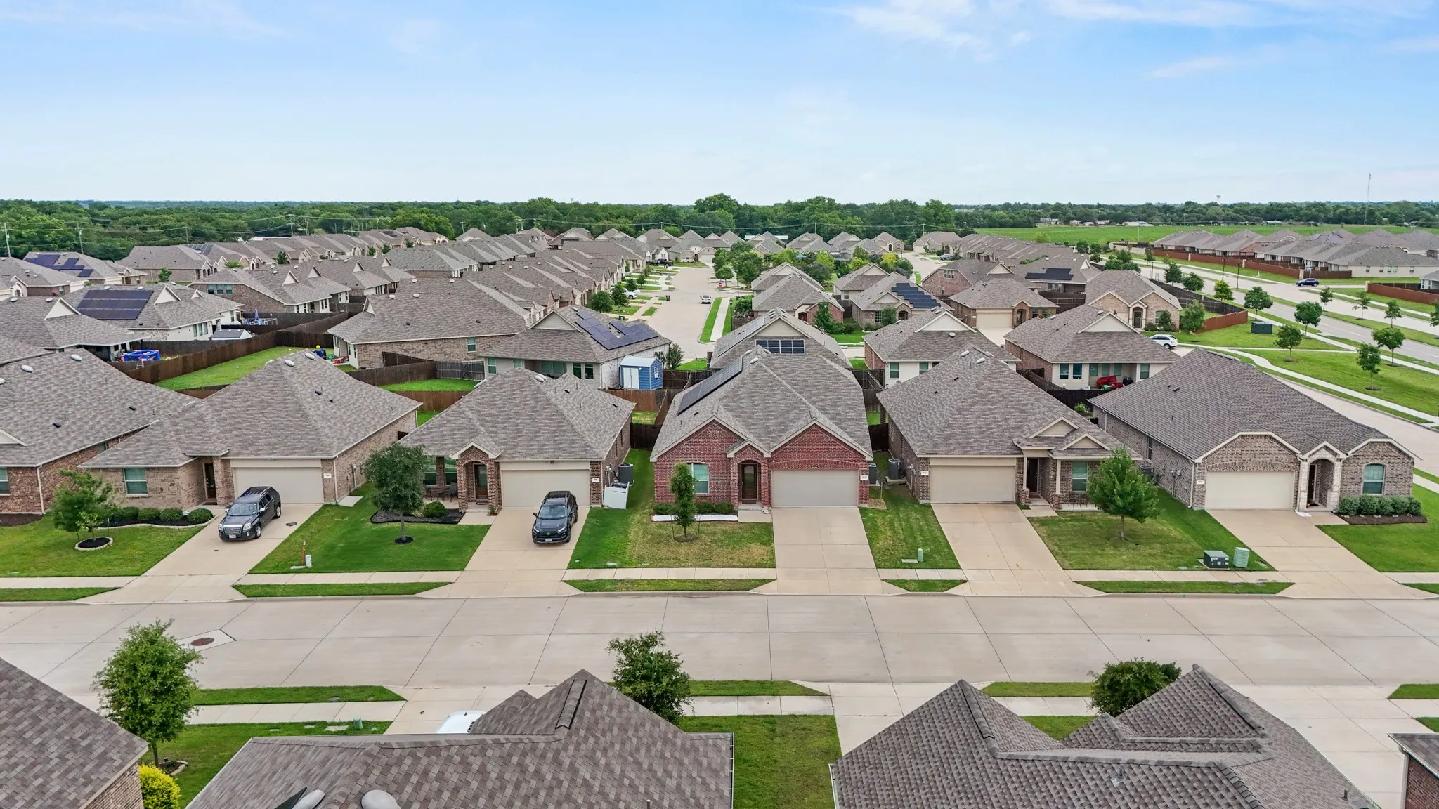 Aerial perspective showcasing a residential neighborhood with uniform-style homes, each featuring a shingled roof, brick or stone facade, and an attached two-car garage