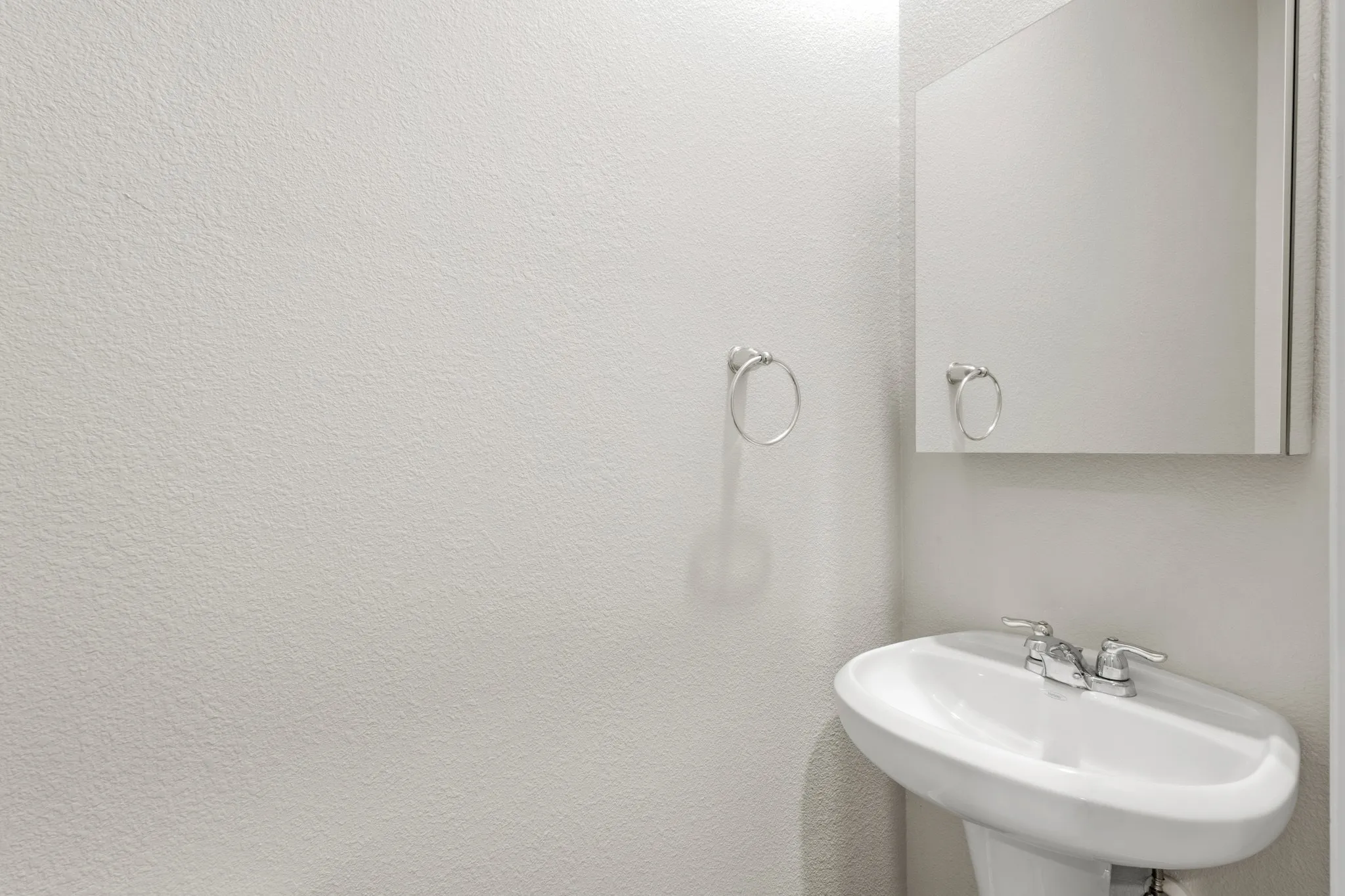 Pedestal sink with chrome fixtures and an overhead mirrored medicine cabinet