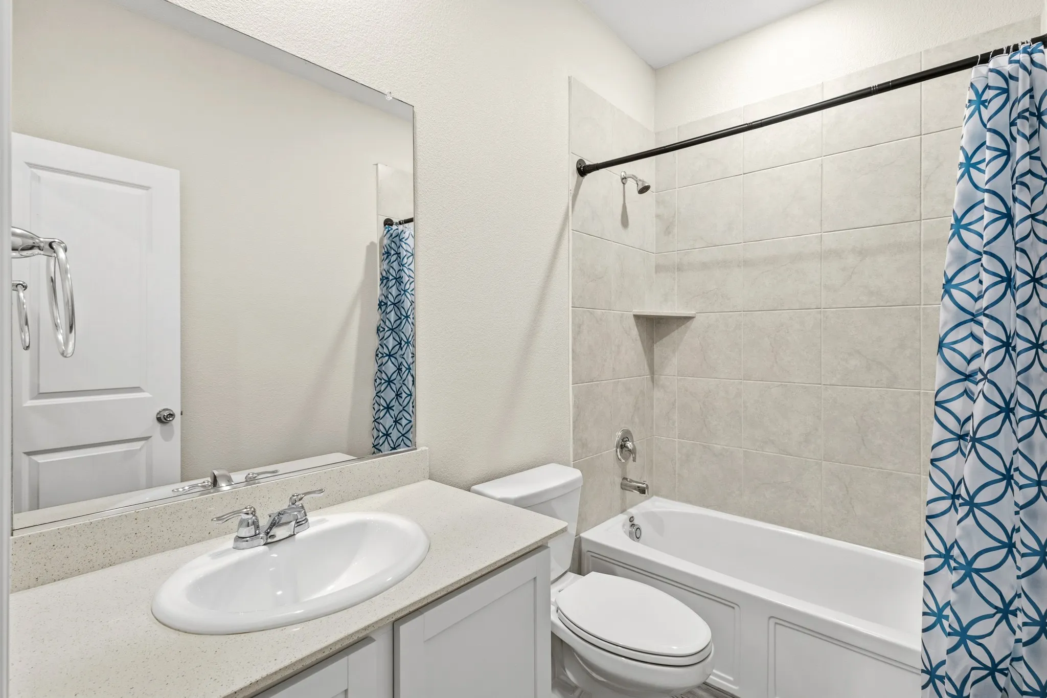 Bathroom featuring a single vanity with a light-toned countertop, an undermount sink, and chrome fixtures