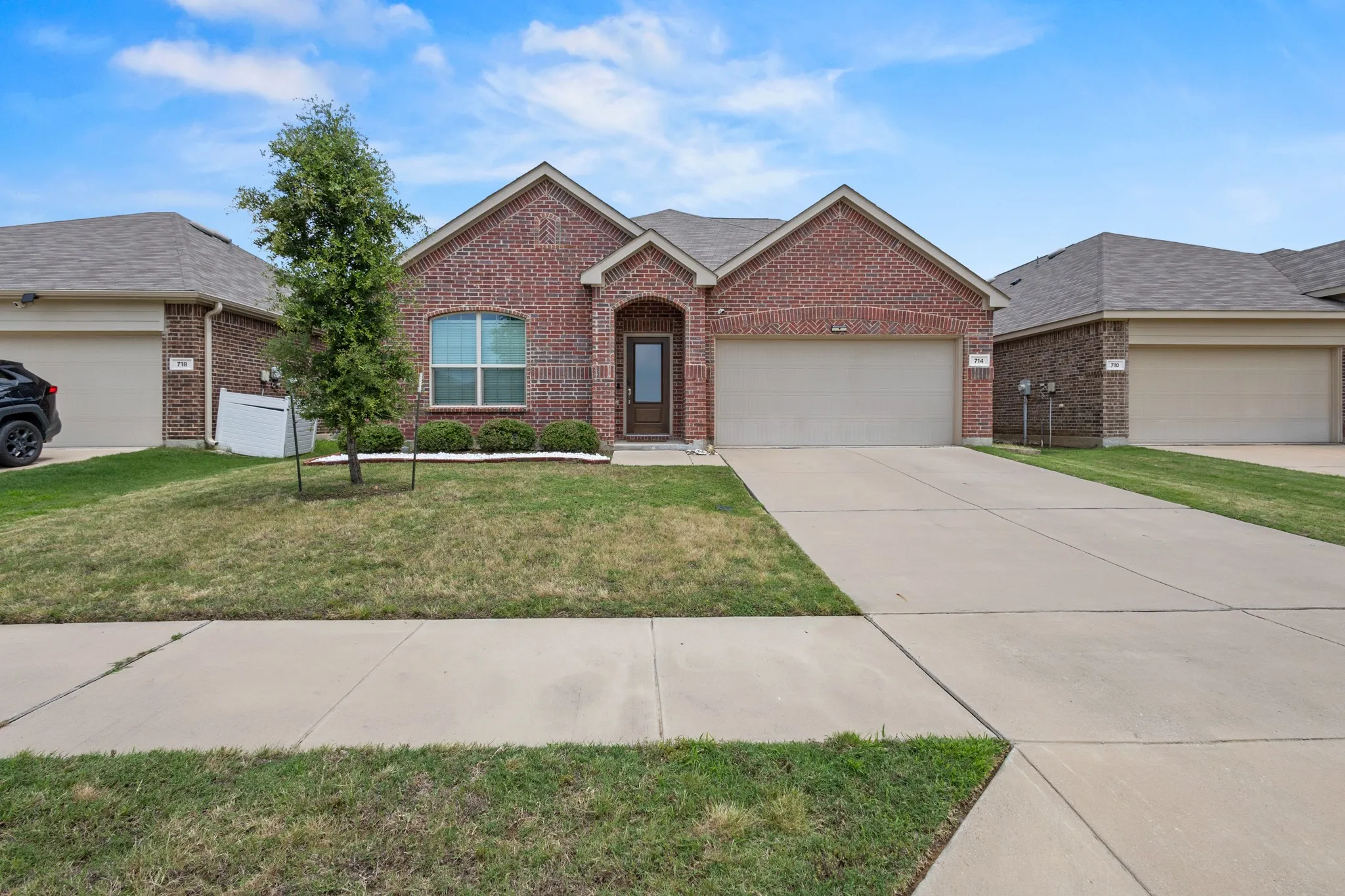 Brick exterior featuring an arched entryway, integrated garage, and a concrete driveway