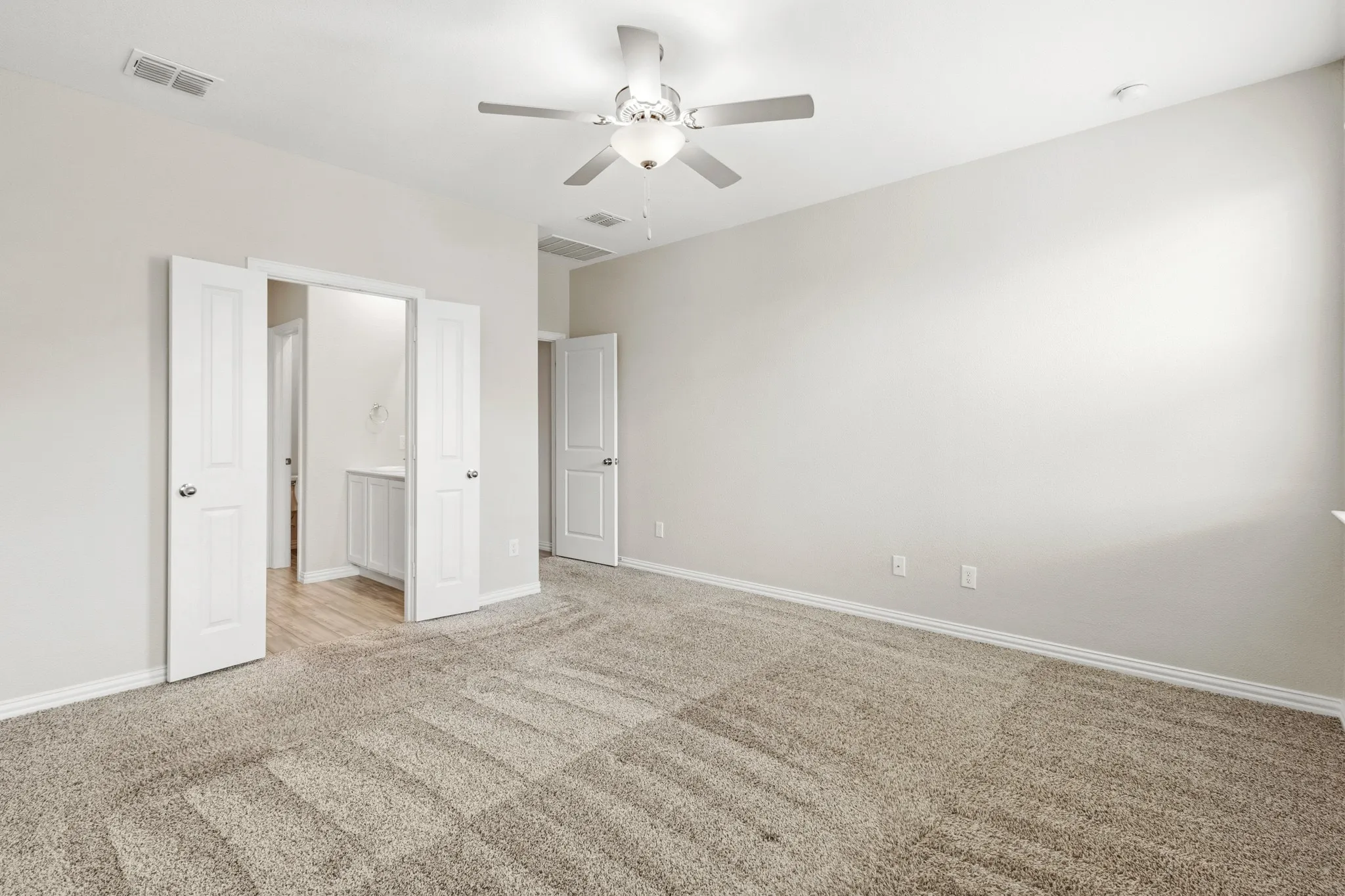 Spacious room with neutral carpet, light gray wall paint, and white trim