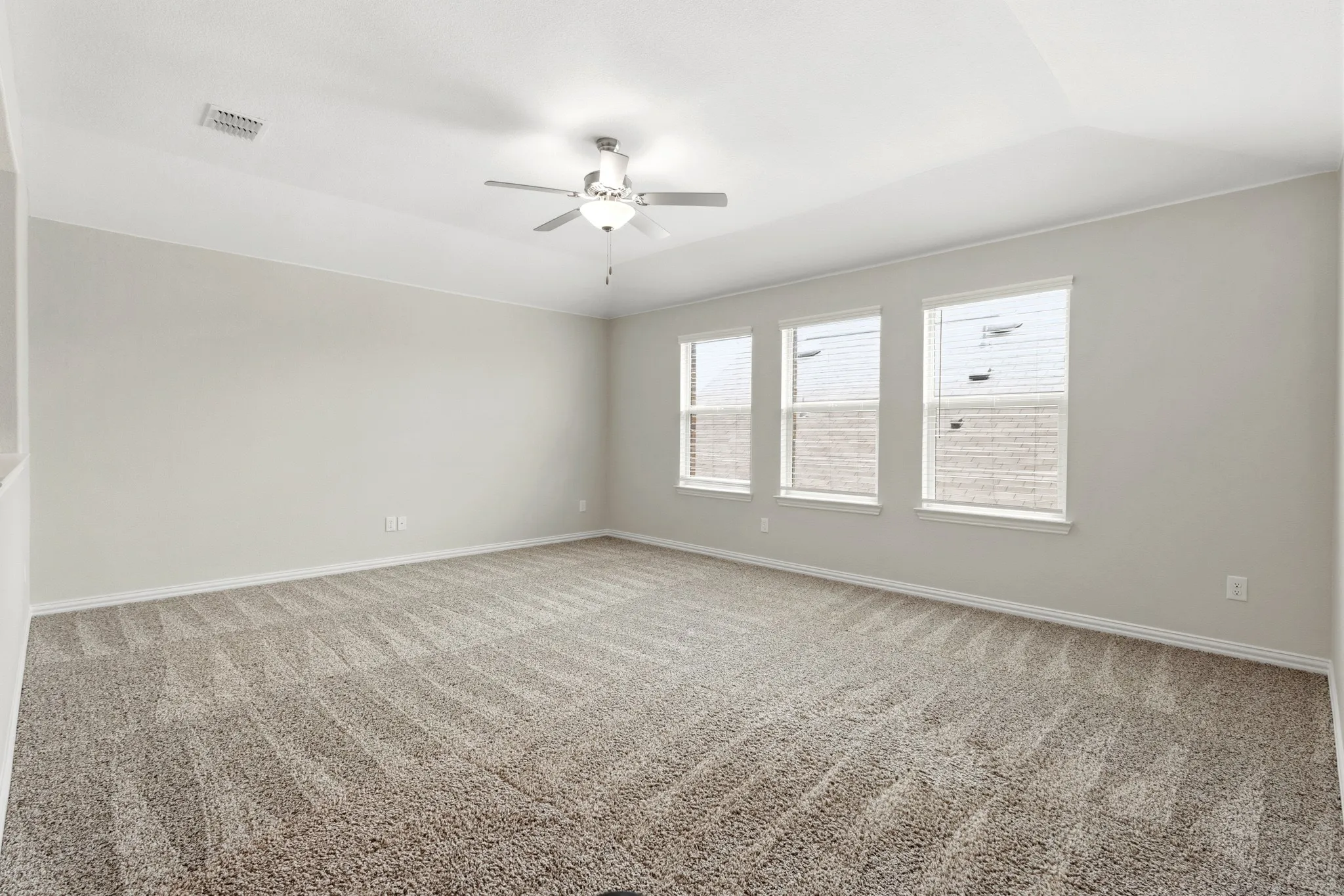 Spacious room featuring neutral carpeting, light-toned walls, and a ceiling fan with integrated lighting