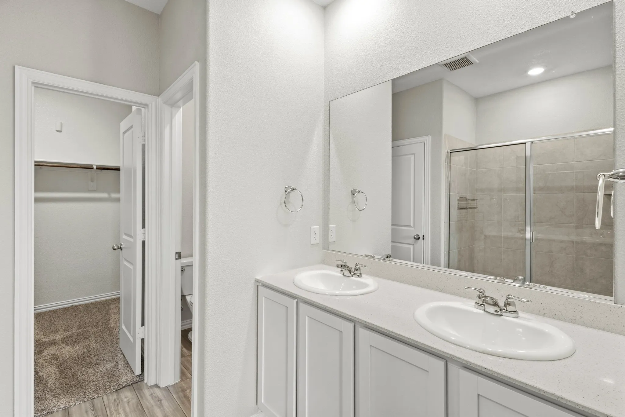 Bathroom featuring a double vanity with white cabinetry and an integrated countertop with two undermount sinks