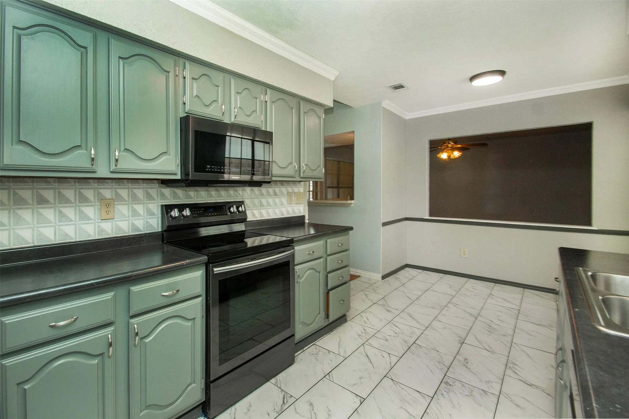 Kitchen featuring green cabinetry, black countertops, a black range, and an over-the-range microwave