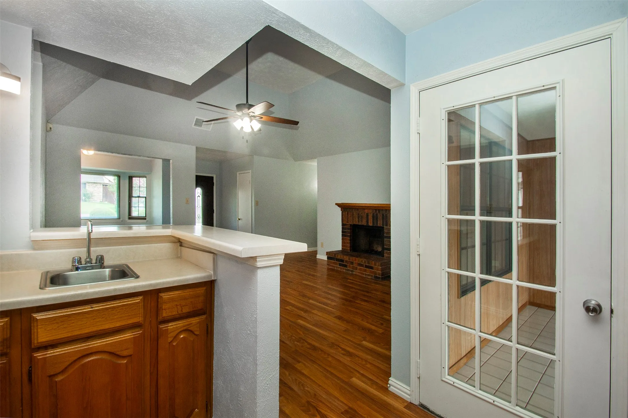 Kitchenette area featuring a stainless steel sink, wood cabinetry, and a countertop bar