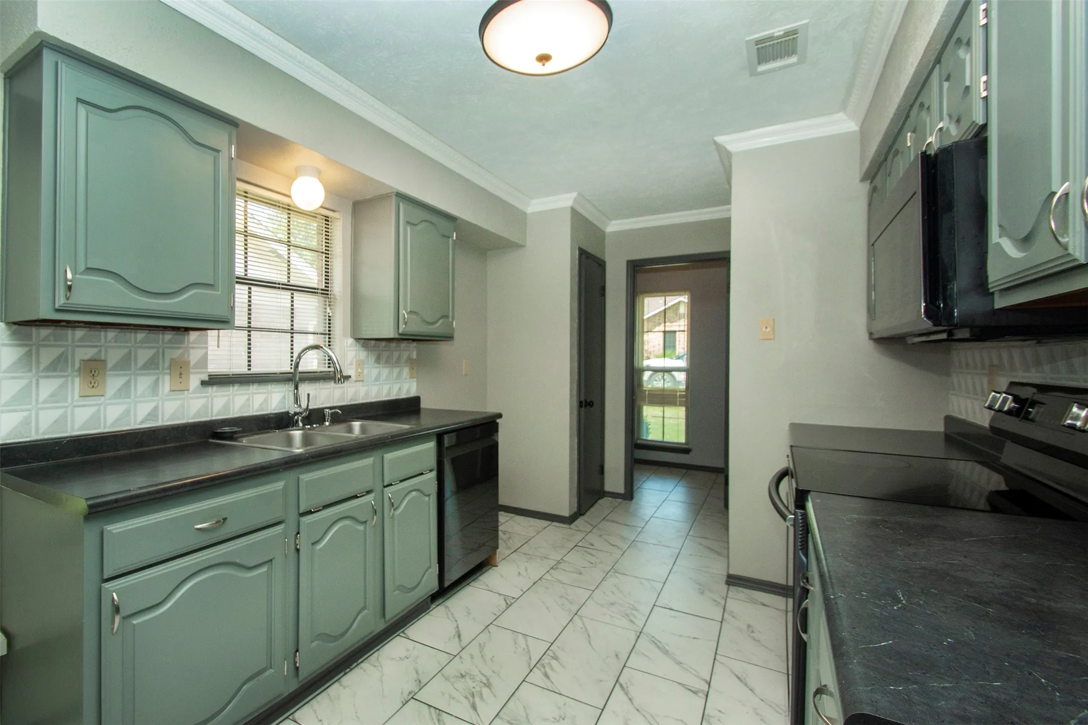 Kitchen featuring painted cabinetry, a tile backsplash, dark countertops, and tile flooring