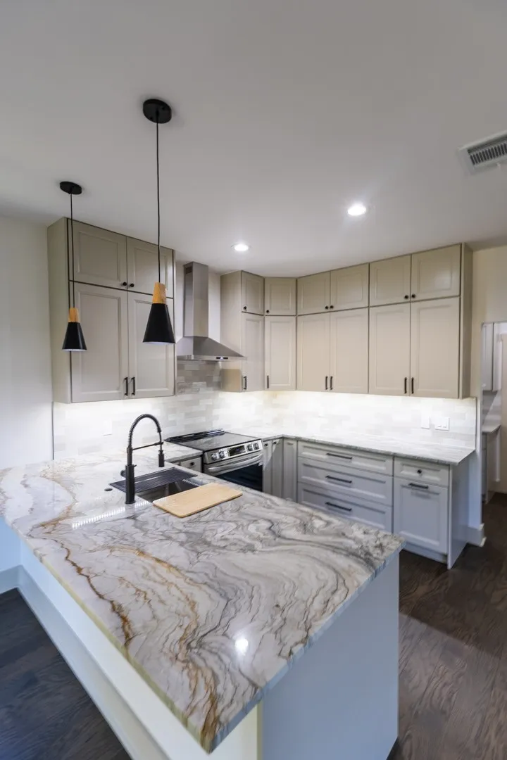 Kitchen featuring a large island with a distinctive veined countertop, pendant lighting, shaker-style cabinetry, and a subway tile backsplash