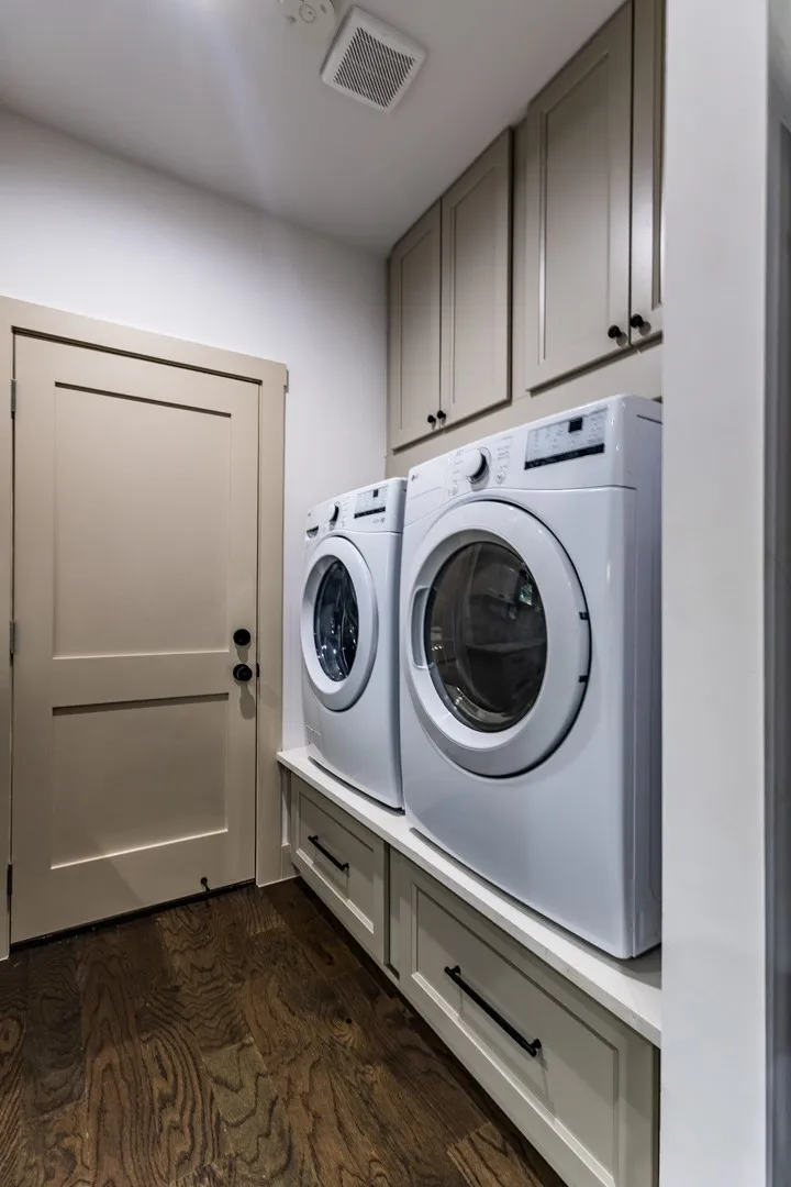 Laundry area features elevated platform with front loading washer and dryer and extra storage