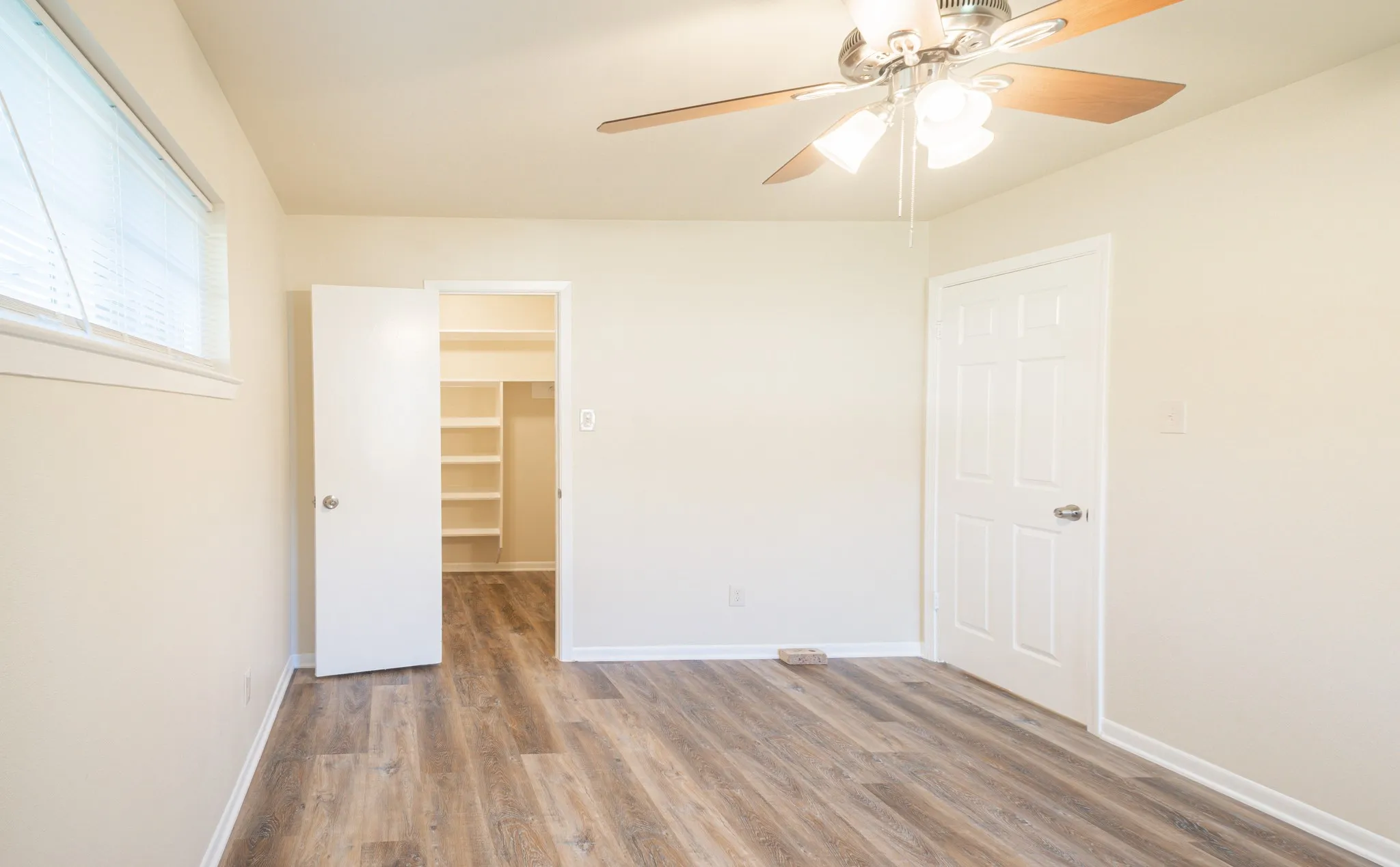 Room featuring wood-finish flooring, a ceiling fan with light fixture, and neutral wall tones