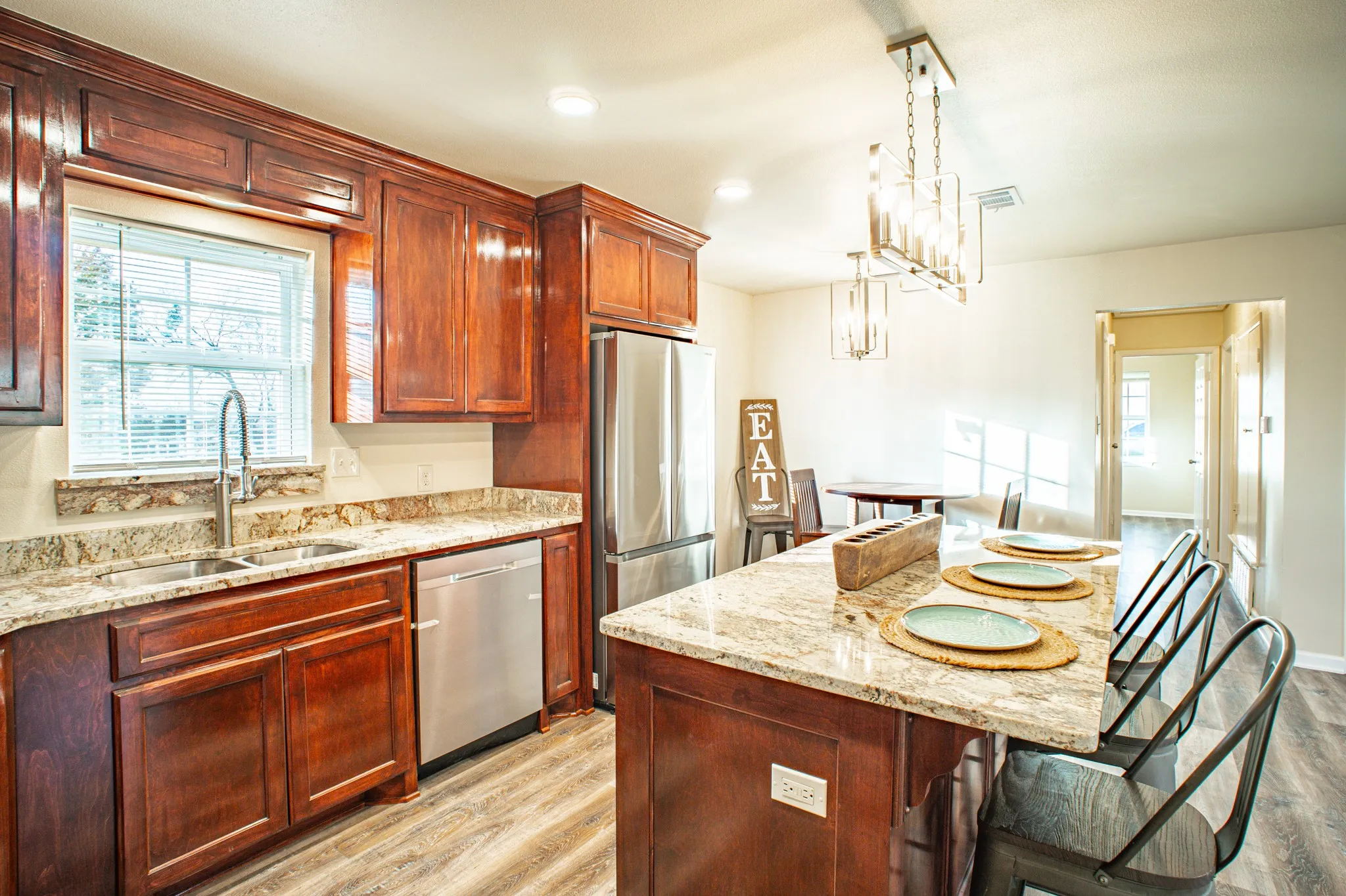 Kitchen featuring wood cabinetry, light-toned countertops, stainless steel appliances, and wood-finish flooring