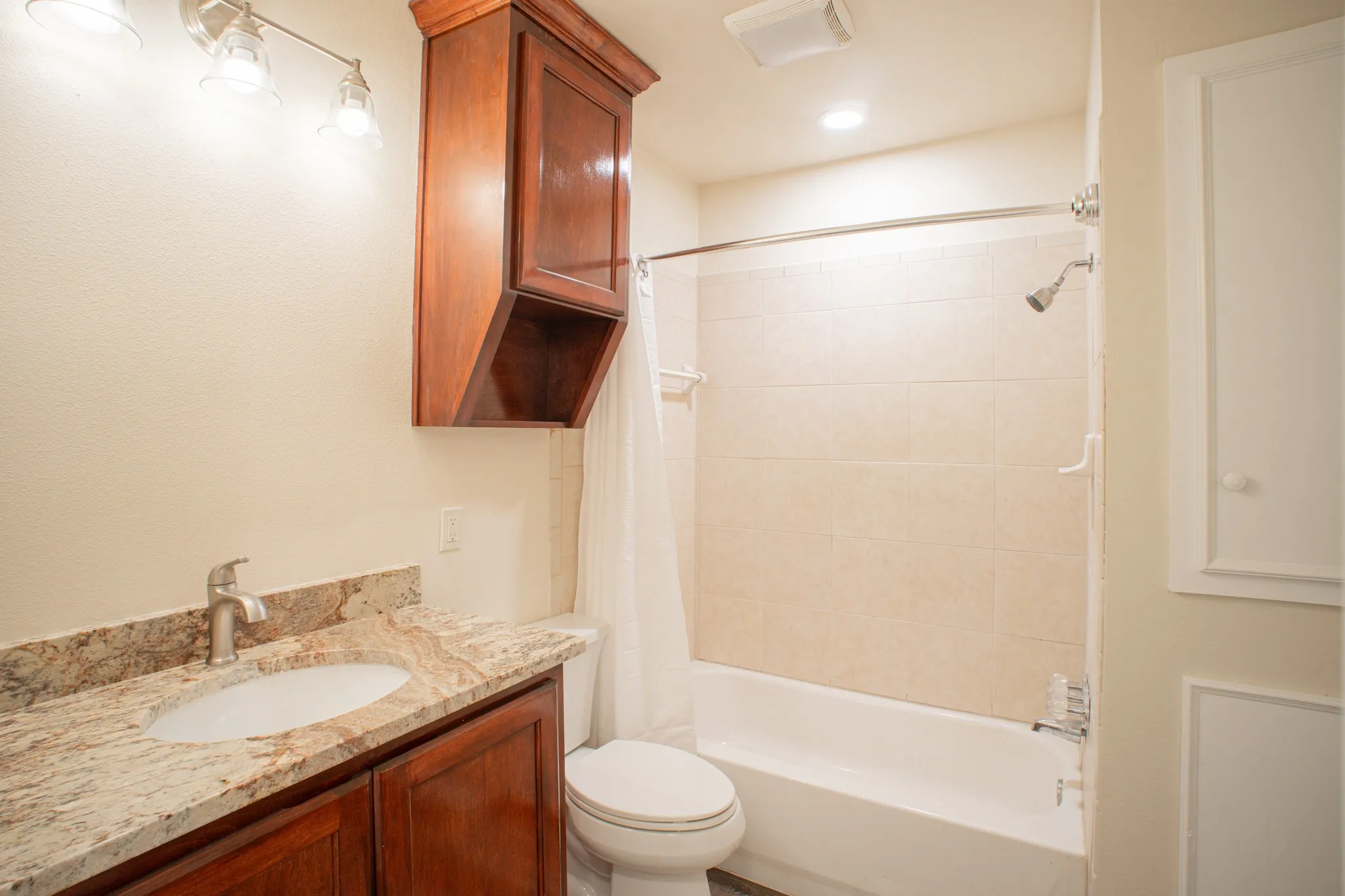 Bathroom featuring a single vanity with a granite countertop, undermount sink, and wood cabinetry