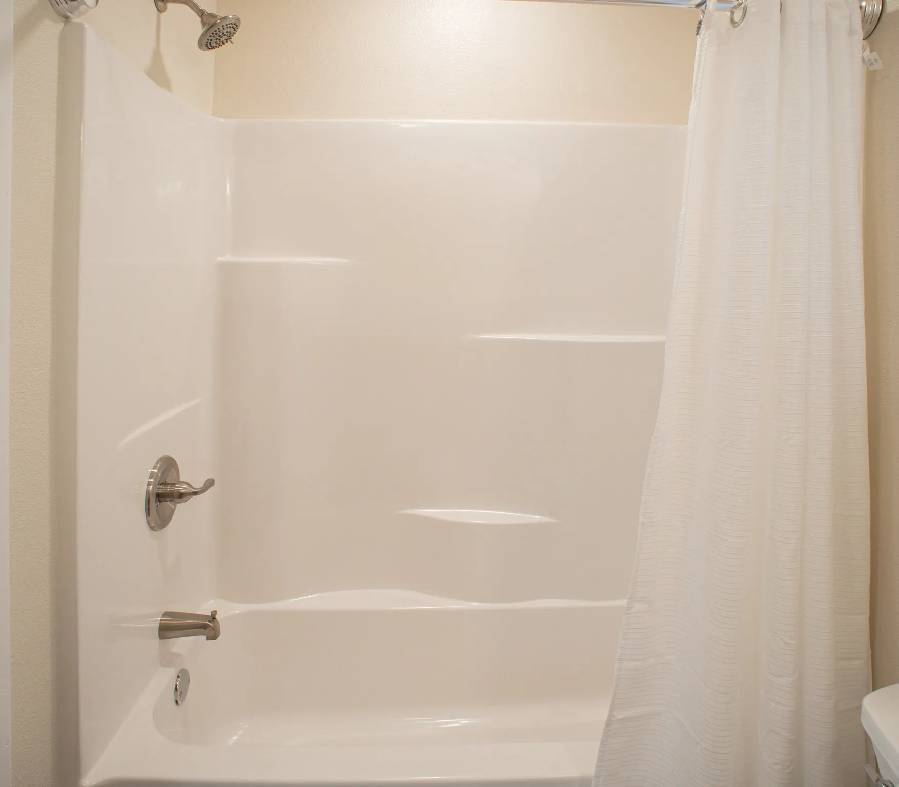White shower-over-tub unit featuring an integrated soap dish and shelving