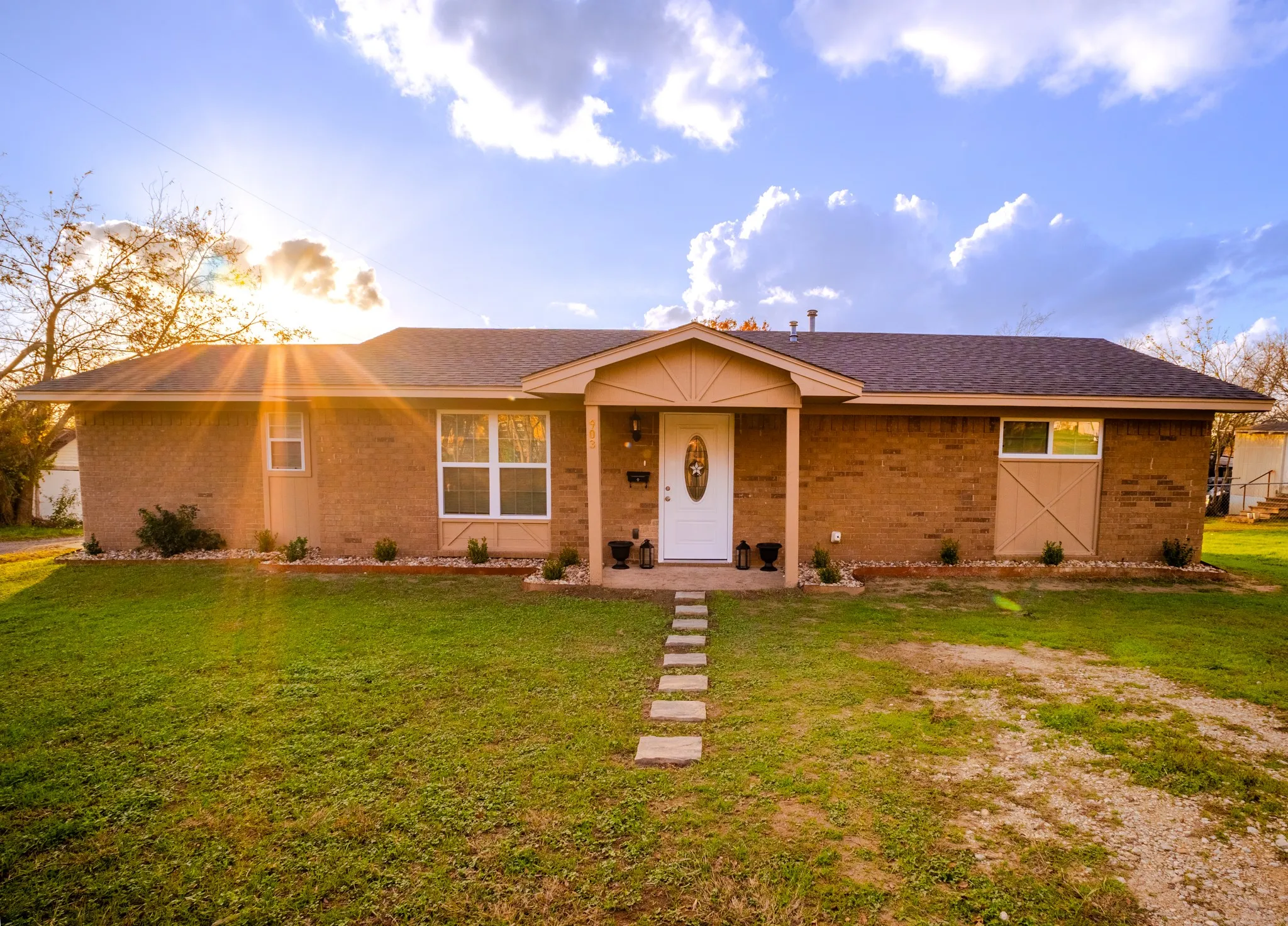 Brick exterior with a covered entryway, a white front door, and a stepping stone pathway