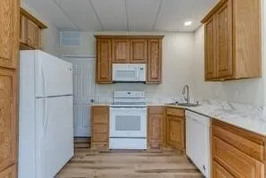 Full kitchen featuring wood-finish cabinetry, white appliances, and light-toned countertops