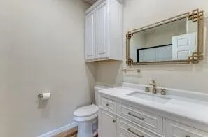 Bathroom featuring a white vanity with integrated sink, gold-finish faucet, and coordinating gold-frame mirror