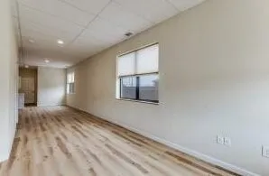 Spacious room featuring wood-finish flooring, light-toned walls, and multiple windows with roller shades