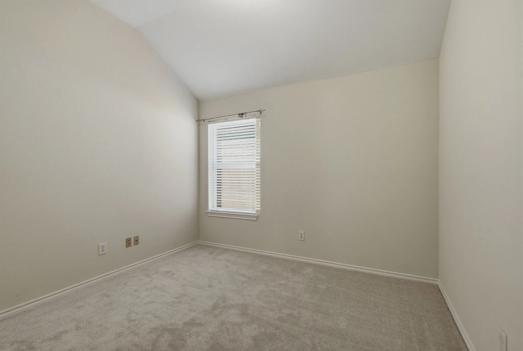 Room featuring light gray carpet, neutral wall paint, and a vaulted ceiling