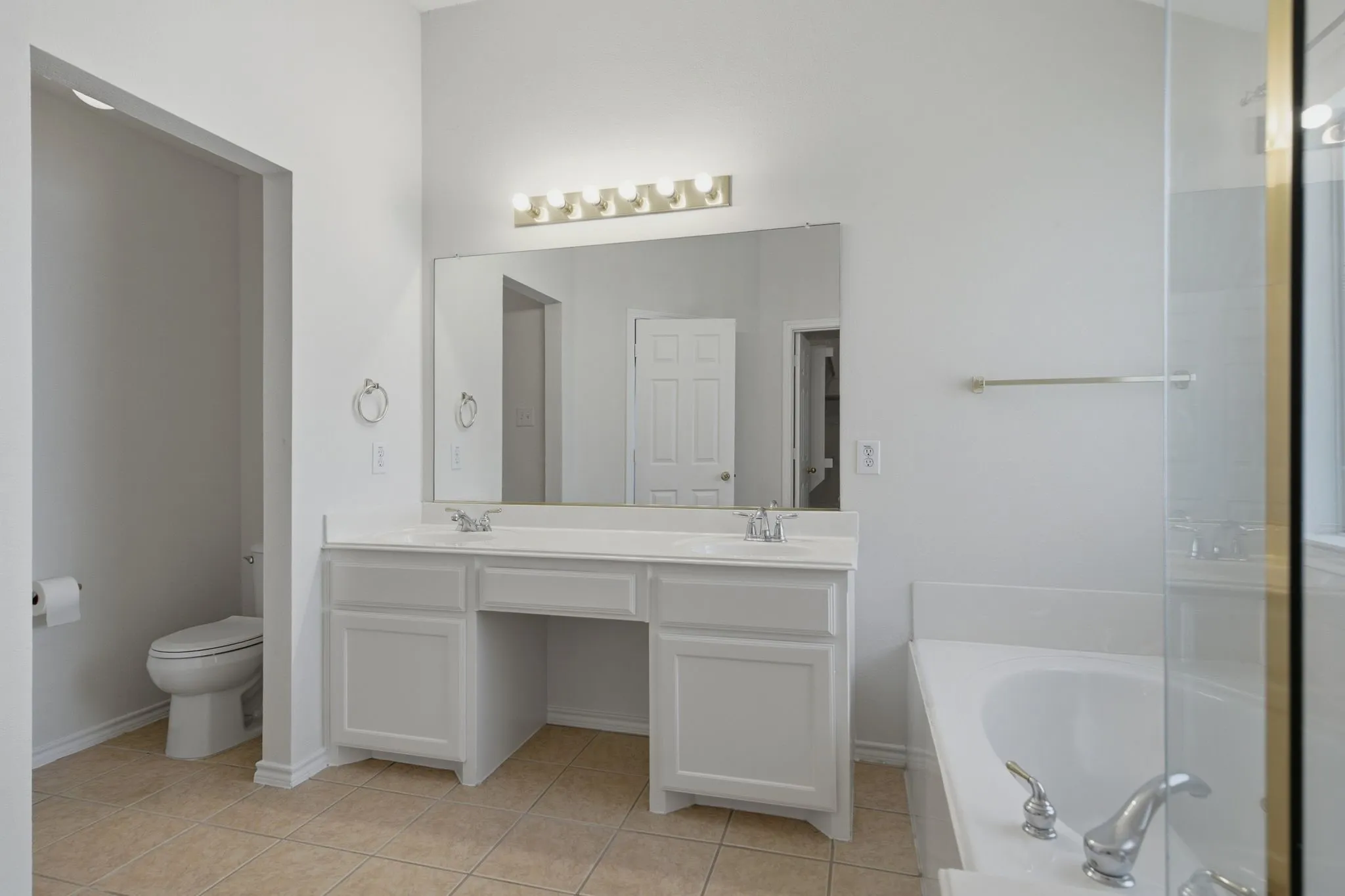Primary Bathroom featuring a dual vanity with a built-in dressing table, framed mirror, and five-bulb vanity lighting