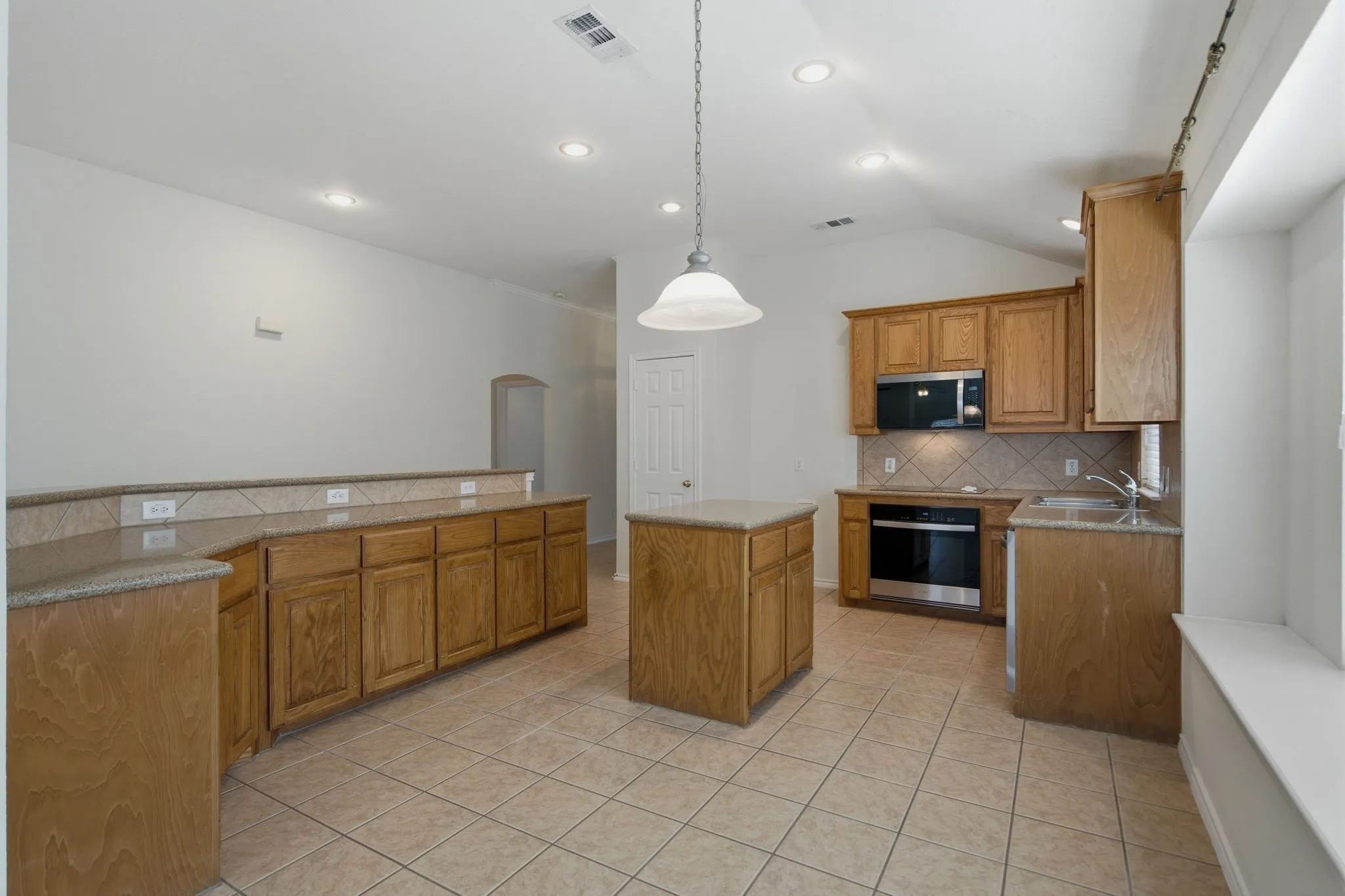 Kitchen featuring a central island, wood cabinetry, stone countertops, and tile flooring