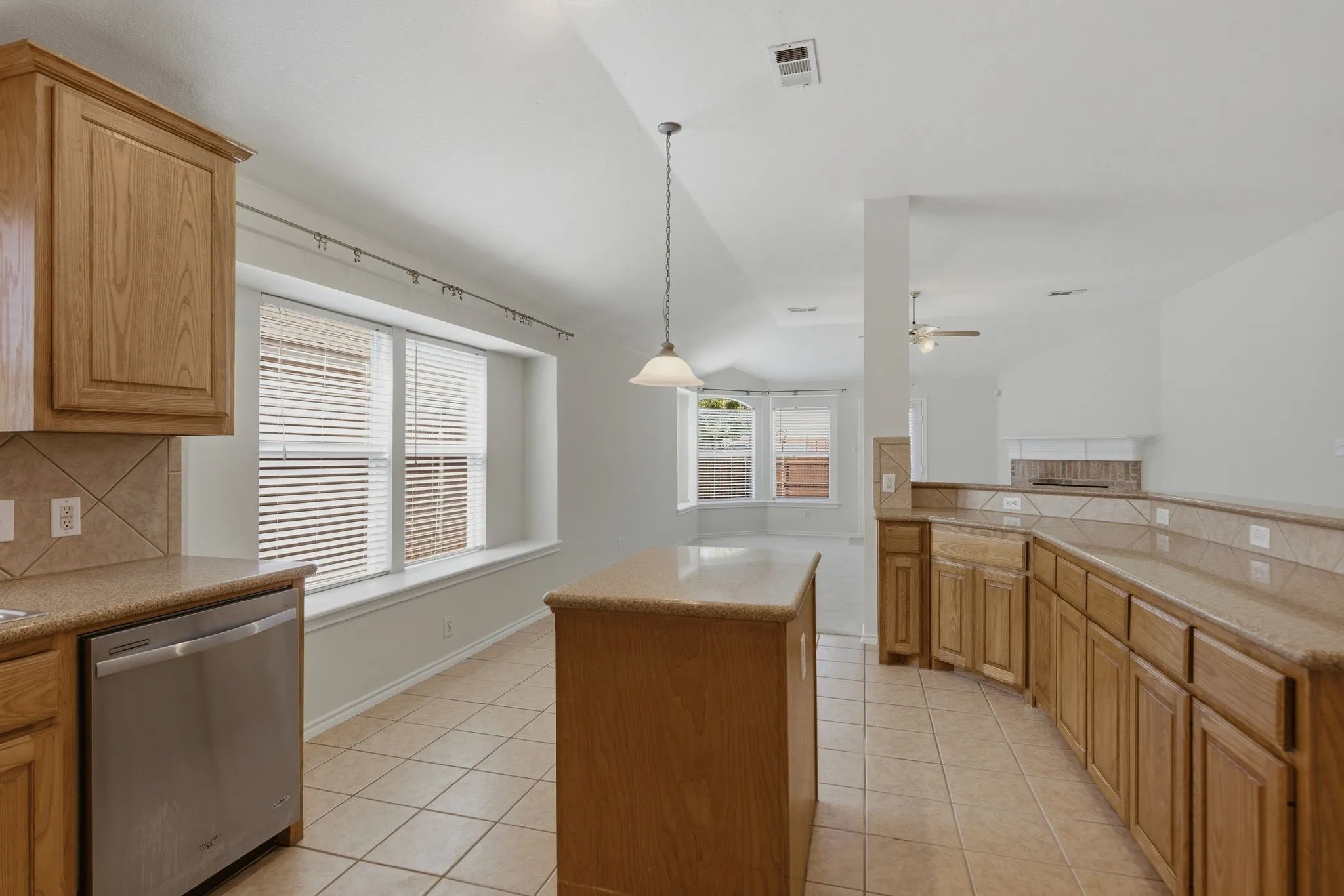 Kitchen featuring a central island, wood cabinetry, tile flooring, and a stainless steel dishwasher