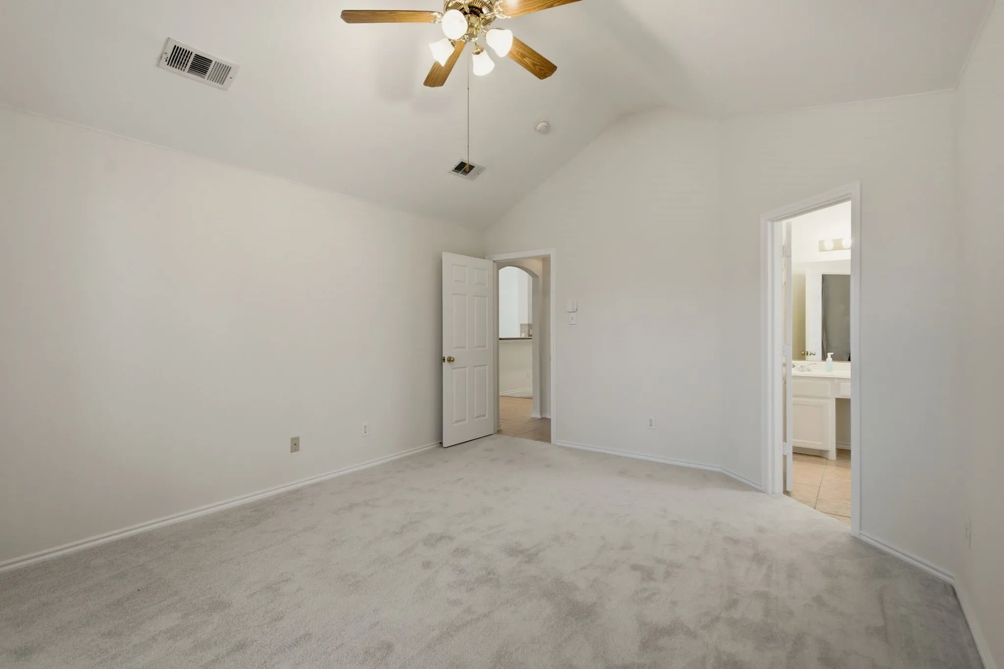 Spacious room featuring vaulted ceilings, light gray carpeting, and white walls