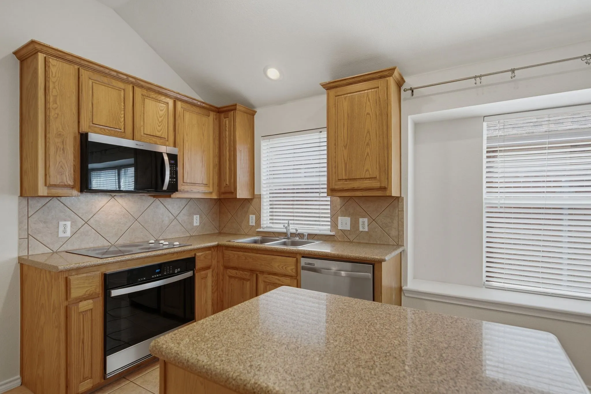 Kitchen featuring wood cabinetry, granite-finish countertops, and a tile backsplash