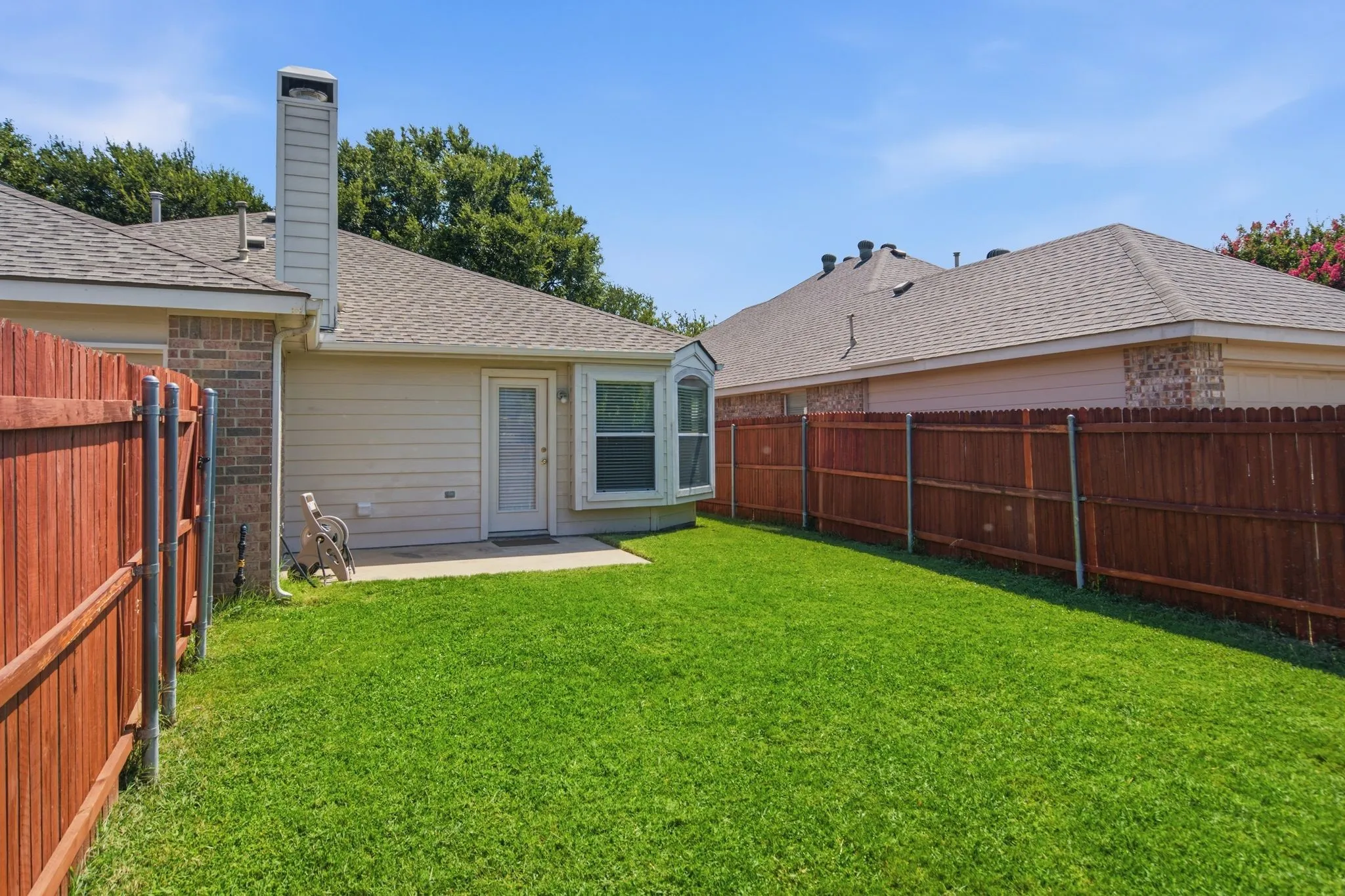 Private backyard featuring a concrete patio, wood fencing, and a bay window